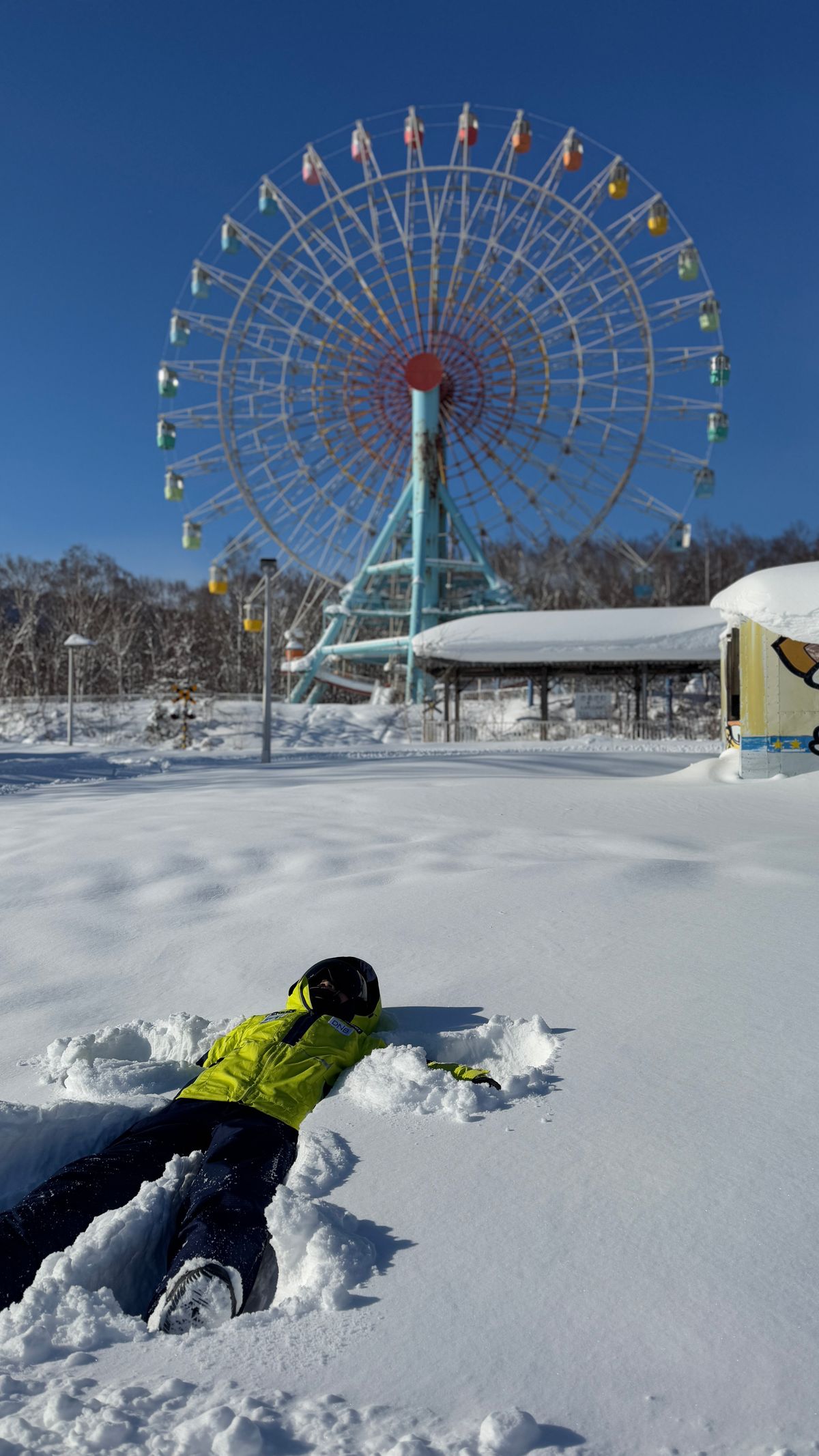 手稻奧林匹亞區的彩色摩天輪,前方雪地上有人躺著做雪天使