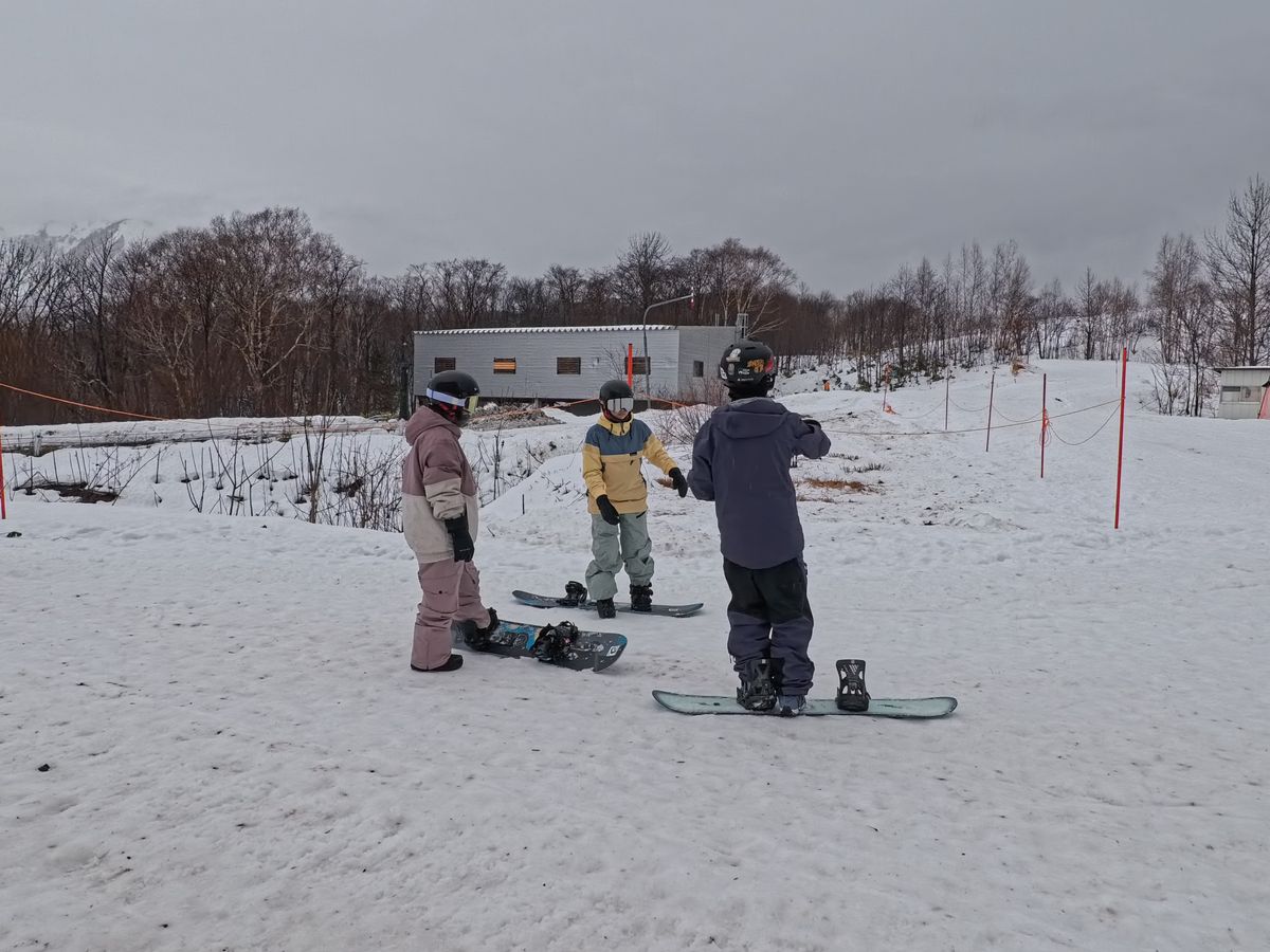 三位單板學員在平緩雪地上練習基礎動作