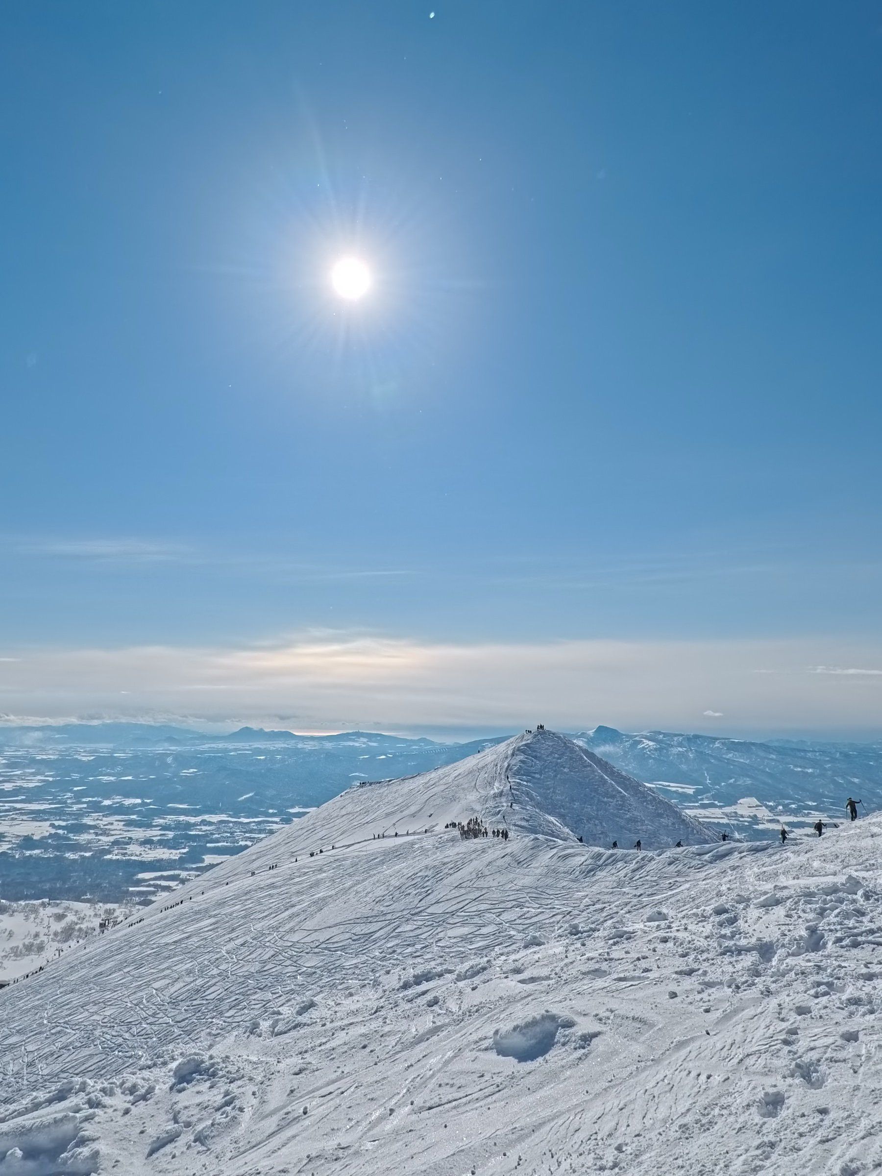 晴天的雪場山頂，遠方是雪山與平原