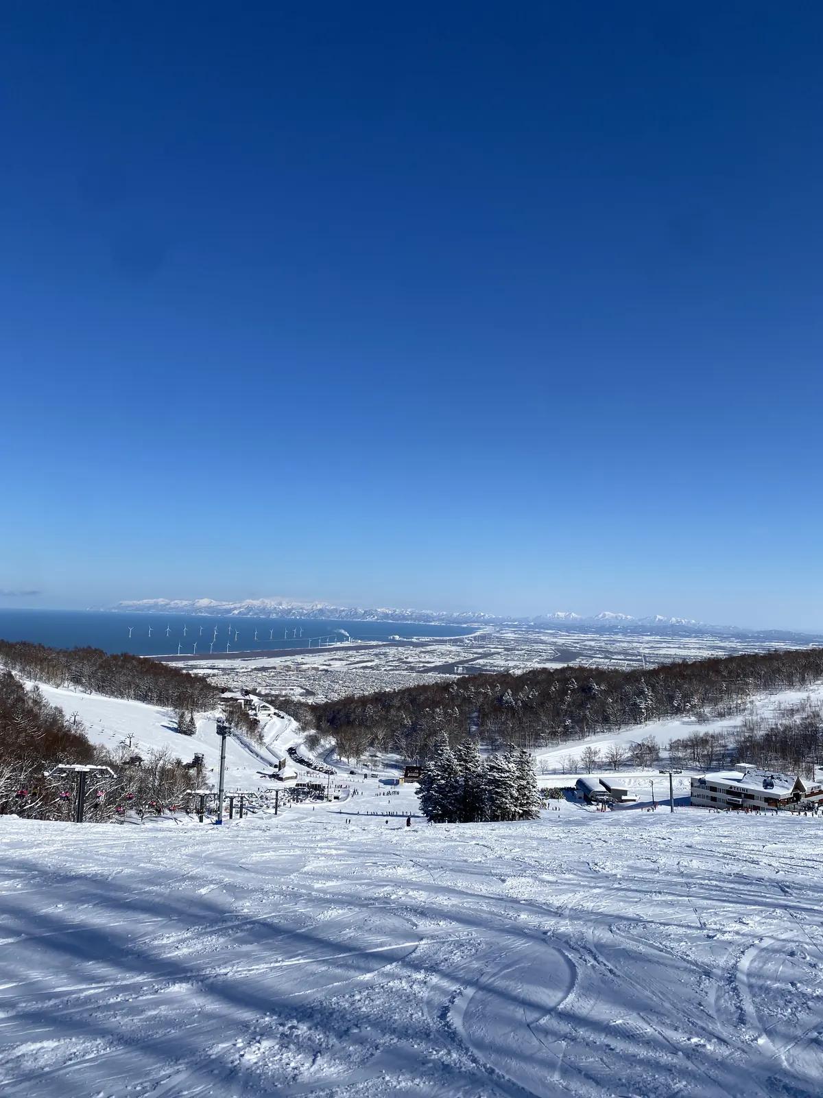 手稻壓雪雪道向下延伸,遠方是石狩灣與札幌市區