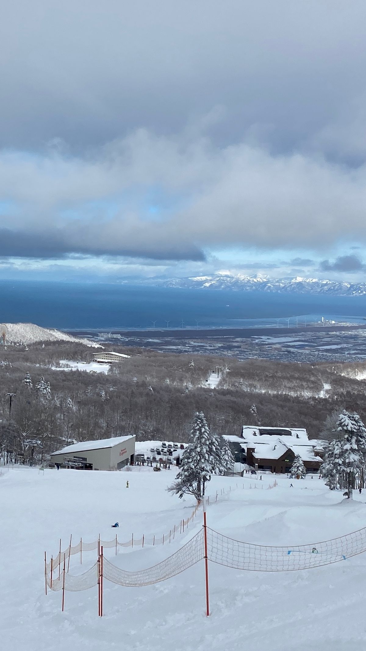 雪道下方的雪場建築與纜車站,遠方是石狩灣與對岸雪山