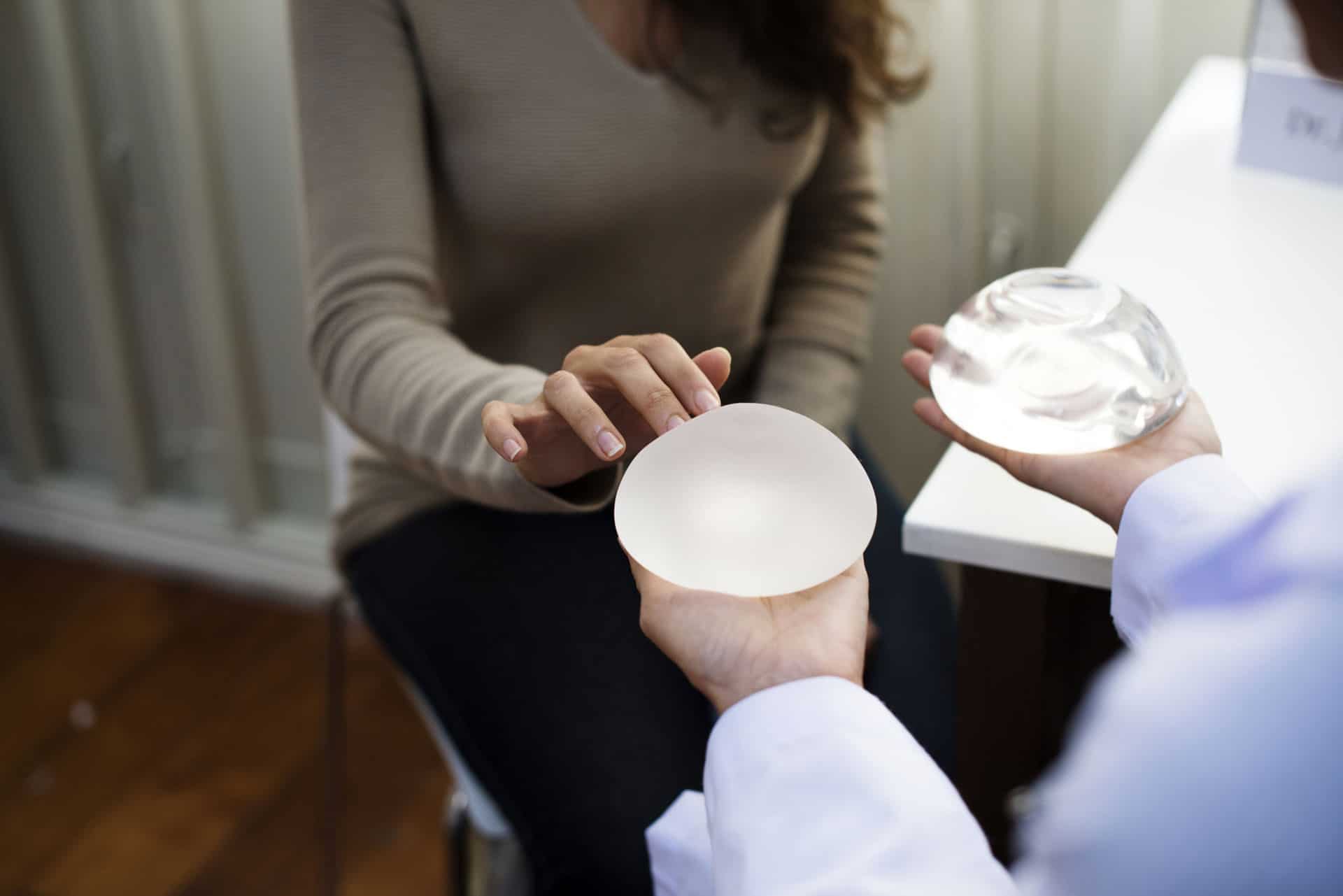 Bilde av en dame som berører et brystimplantat