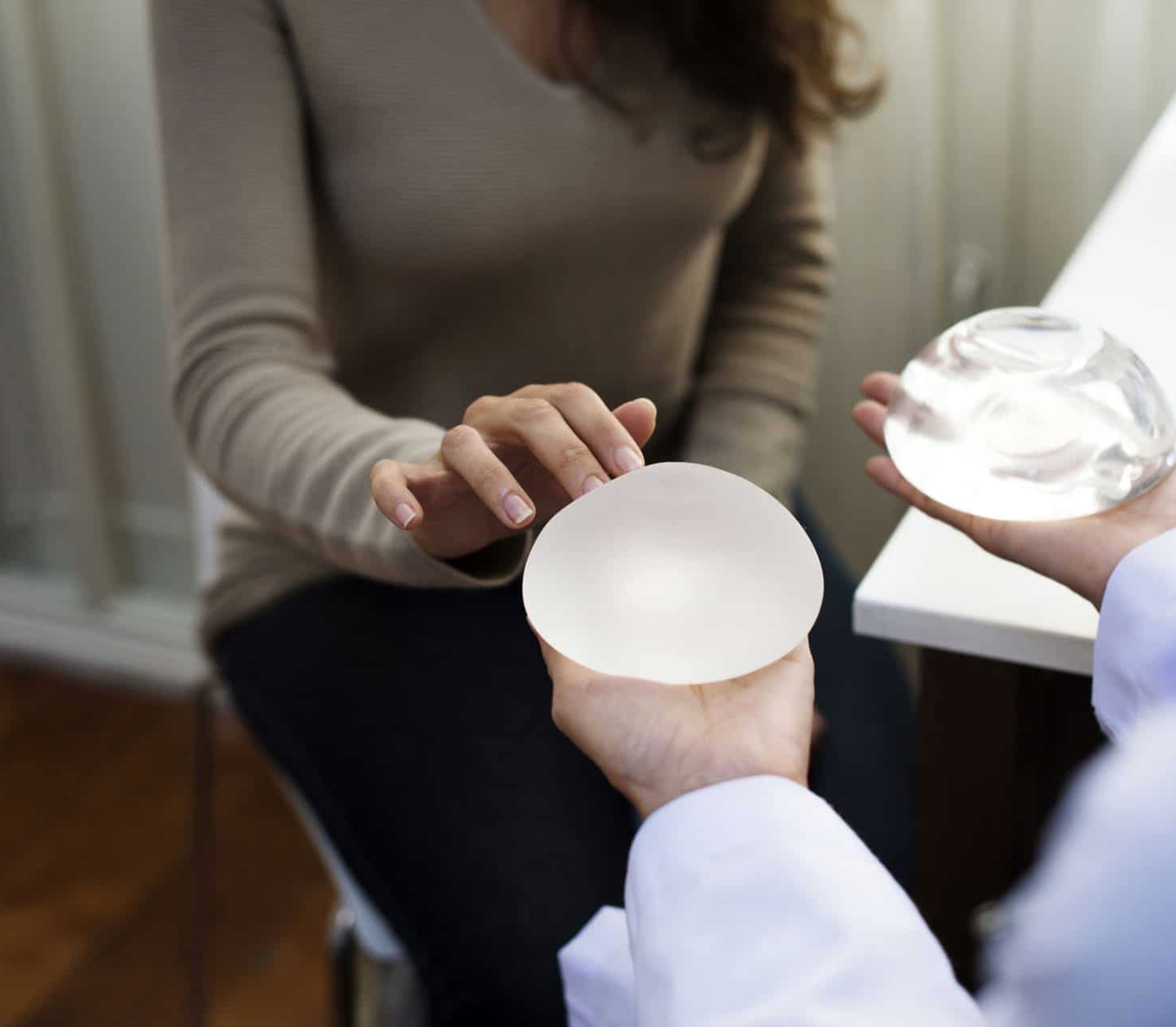 Bilde av en dame som berører et brystimplantat