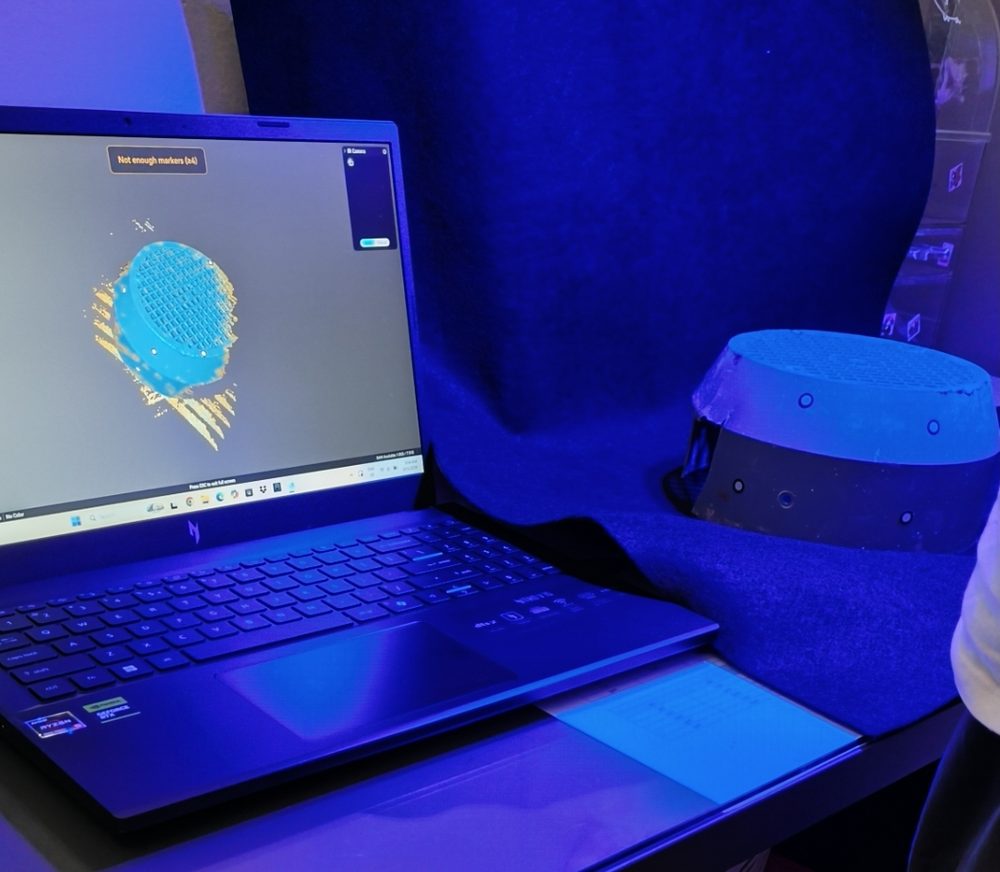 Laptop displaying live 3D scan data beside the motor cover