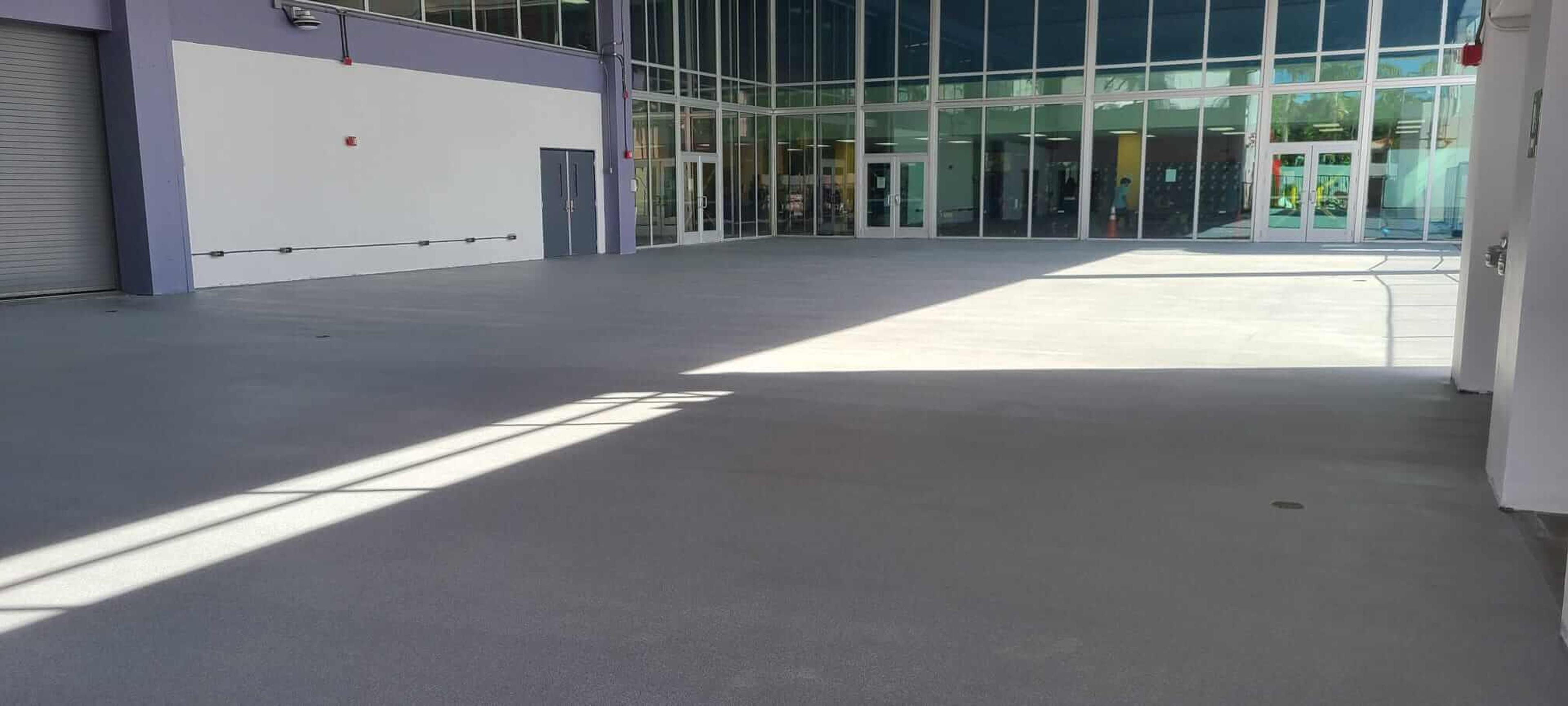 Gray coated concrete floor in a large empty building with a glass curtain wall