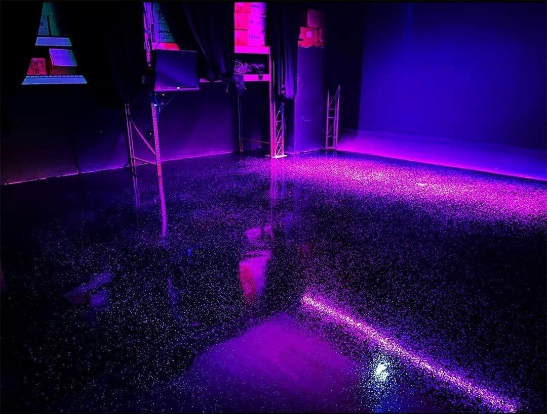Glossy flake epoxy floor reflecting purple event lighting