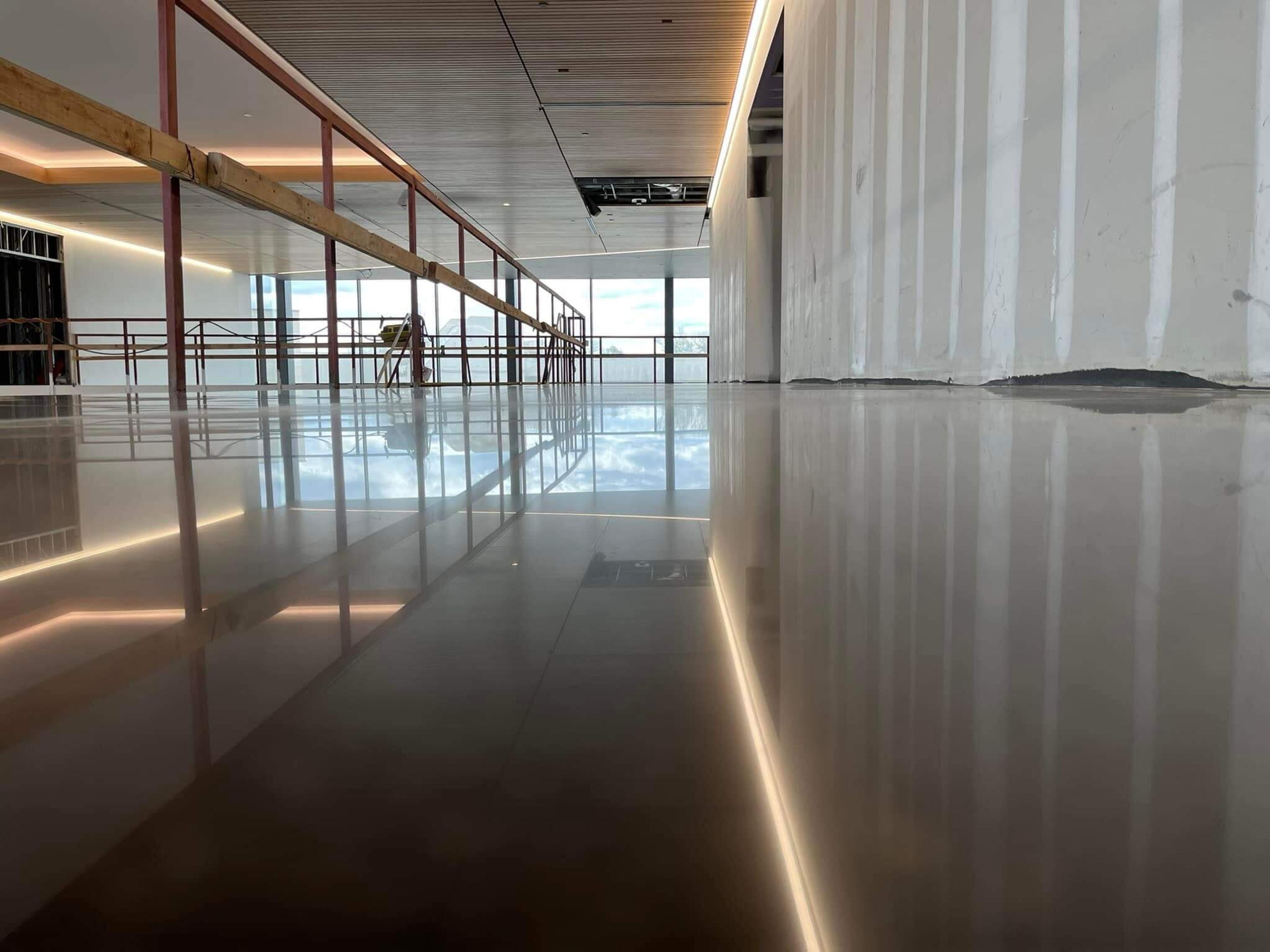 High-gloss polished concrete floor reflecting a glass railing and wood ceiling