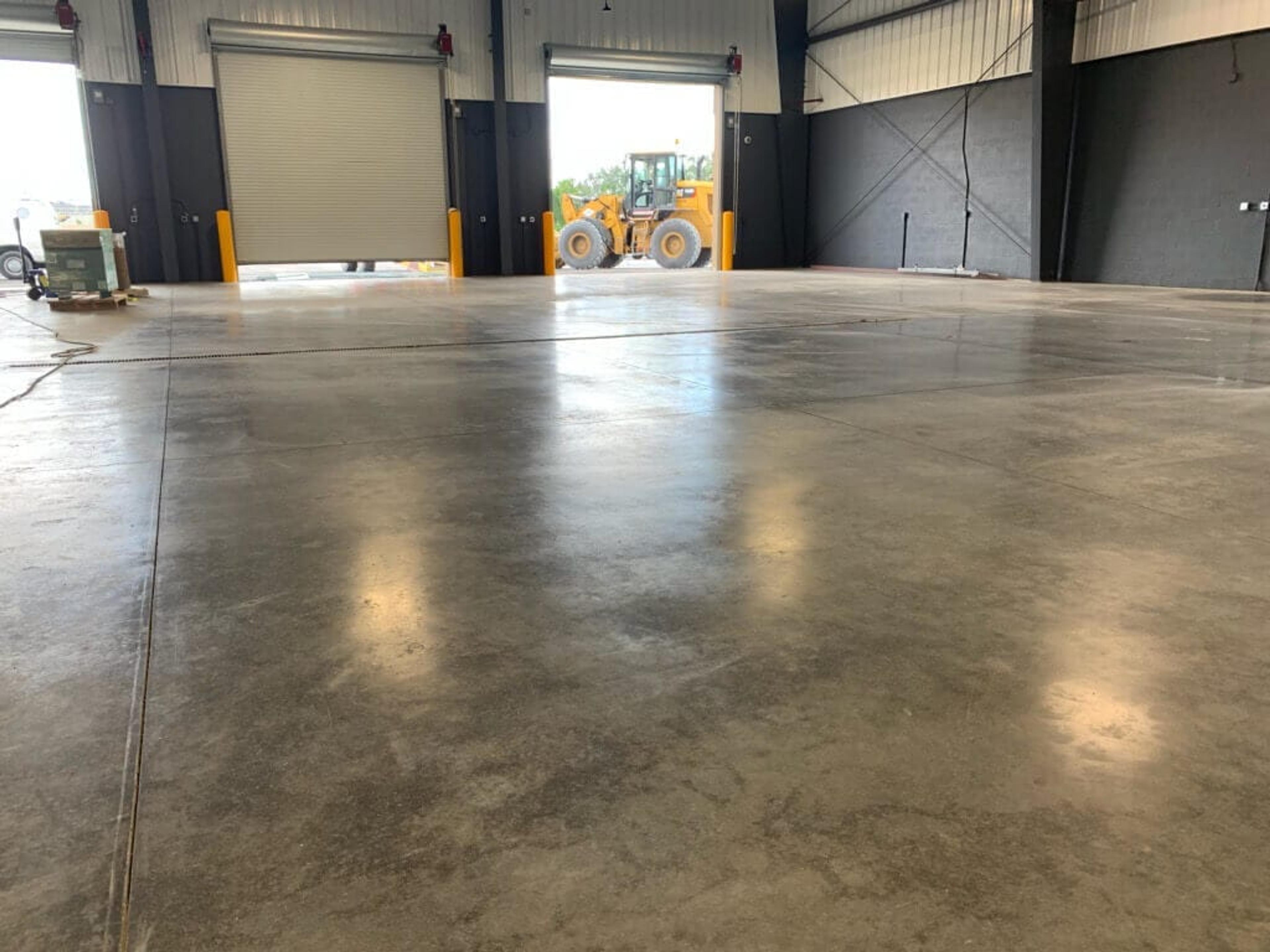 Polished concrete floor in a warehouse with open loading dock doors
