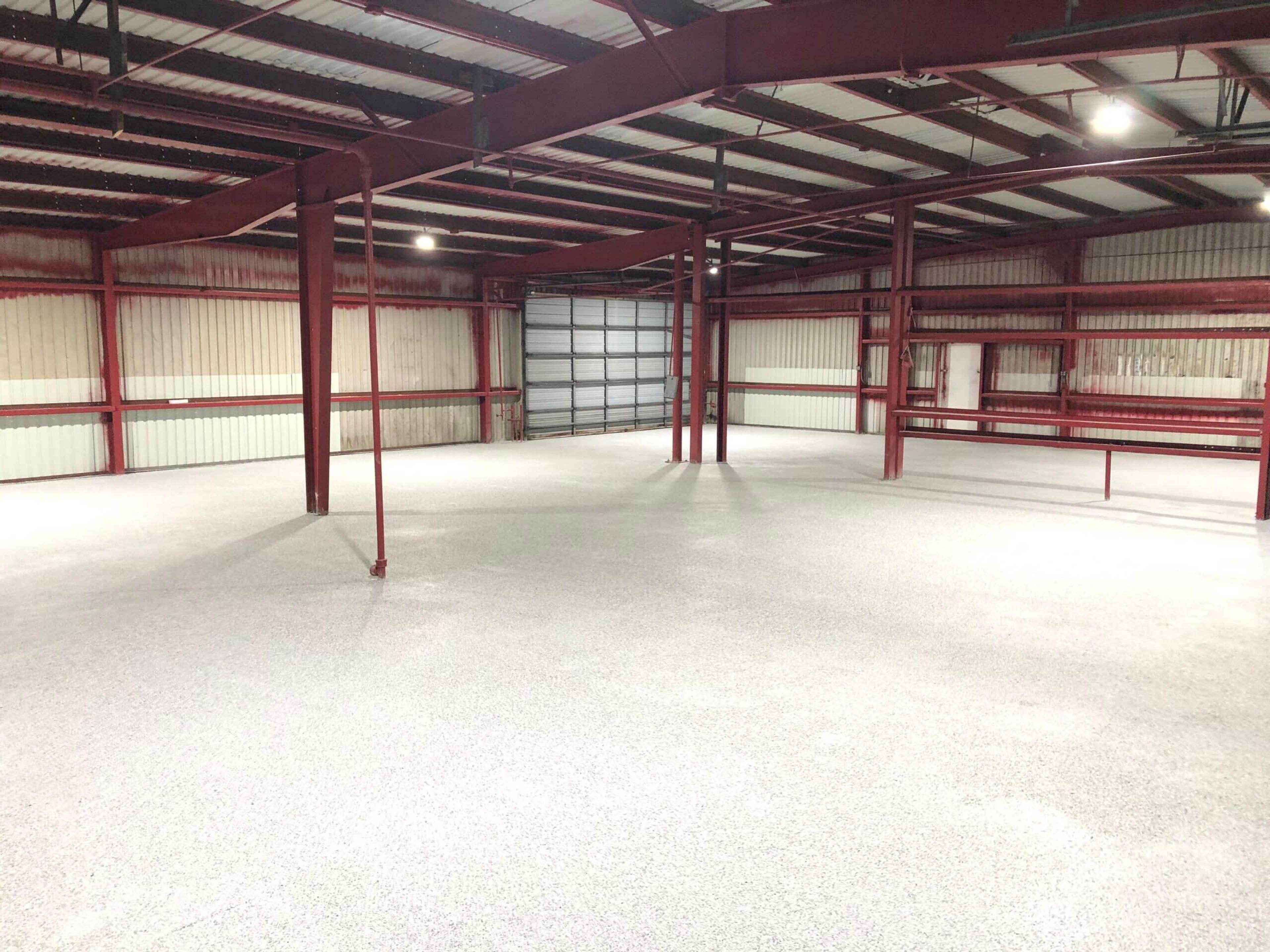 Light speckled epoxy floor in a steel-frame building with red beams