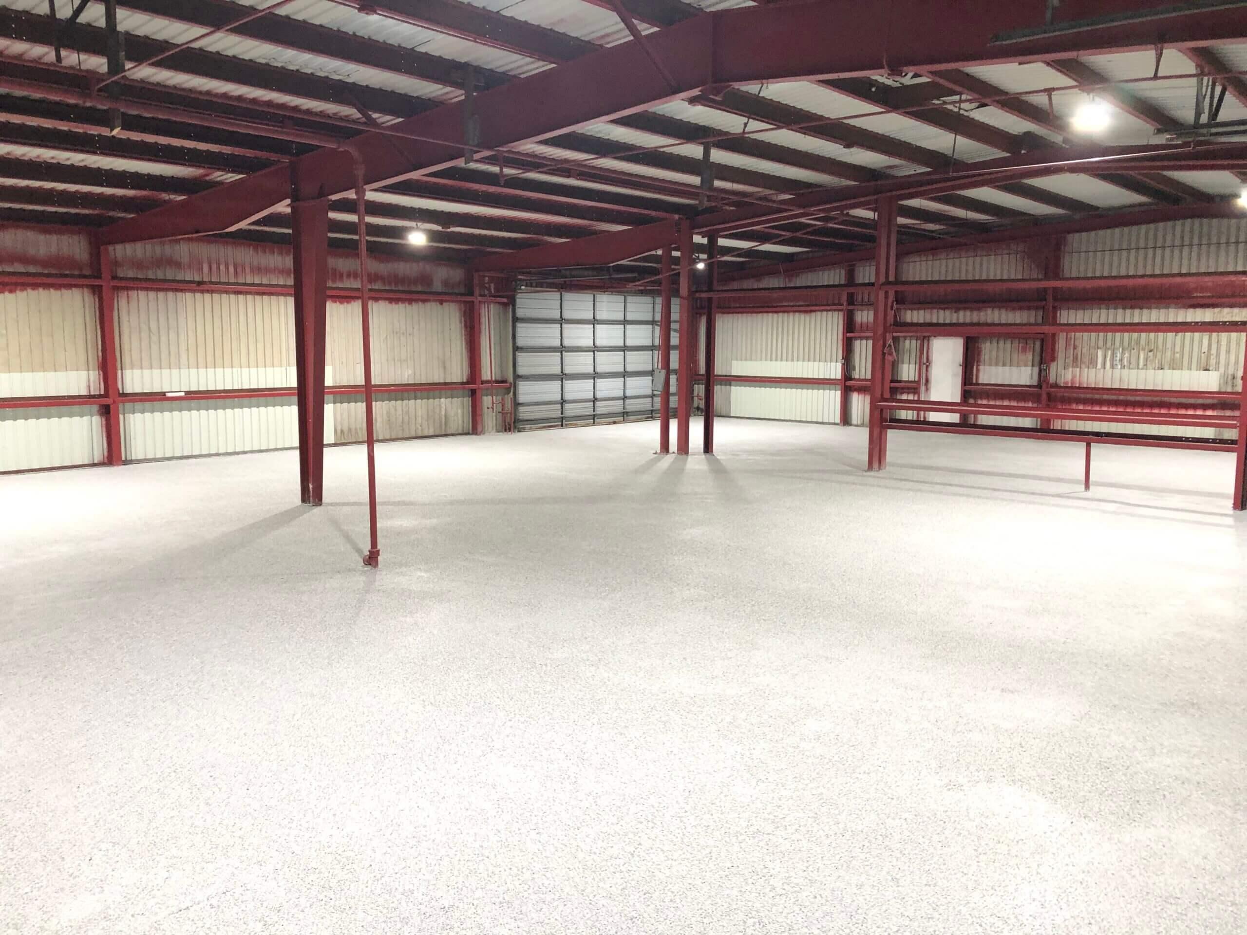 Light speckled epoxy floor in a steel-frame building with red beams