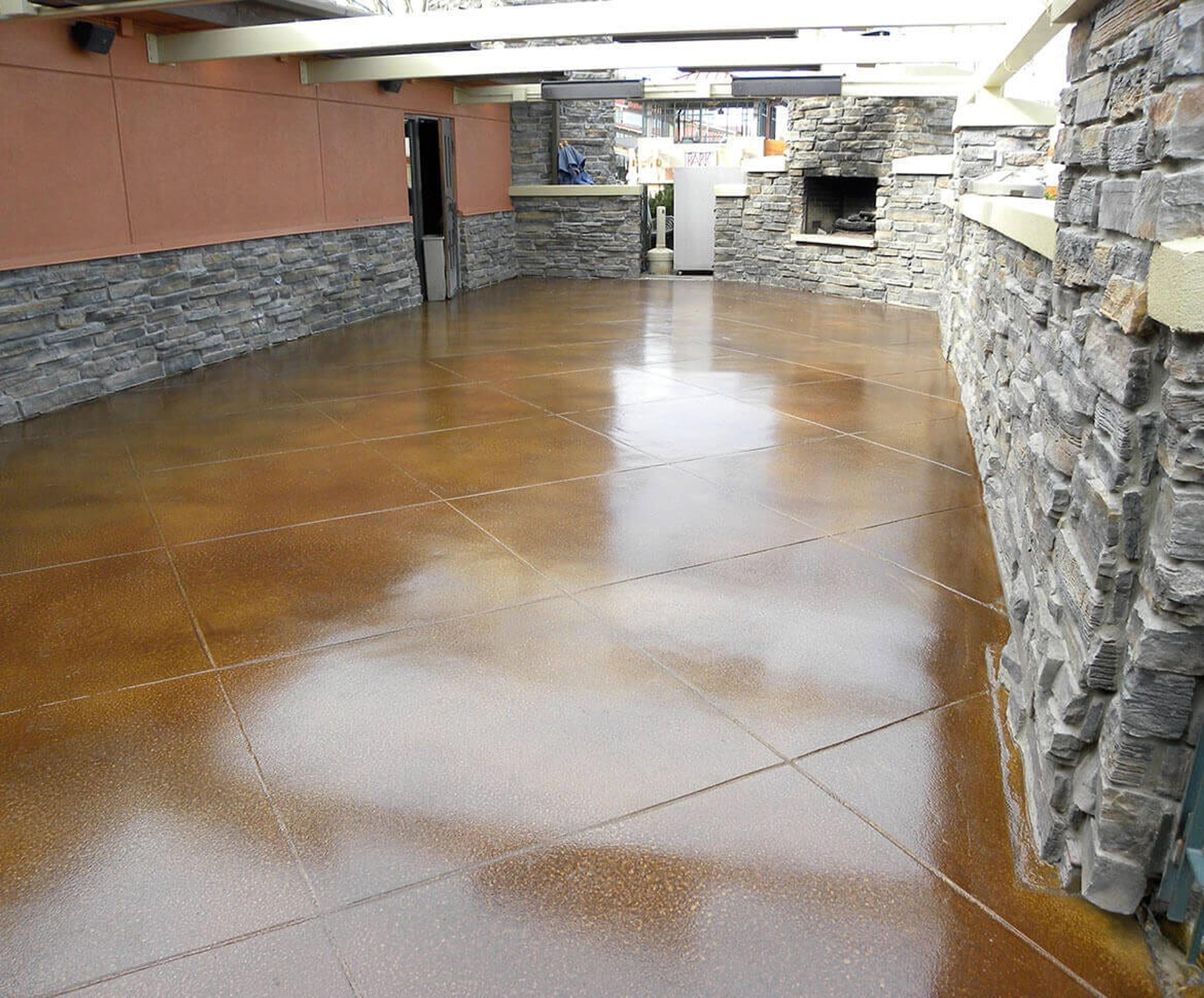 Glossy amber stained concrete floor beside stone walls