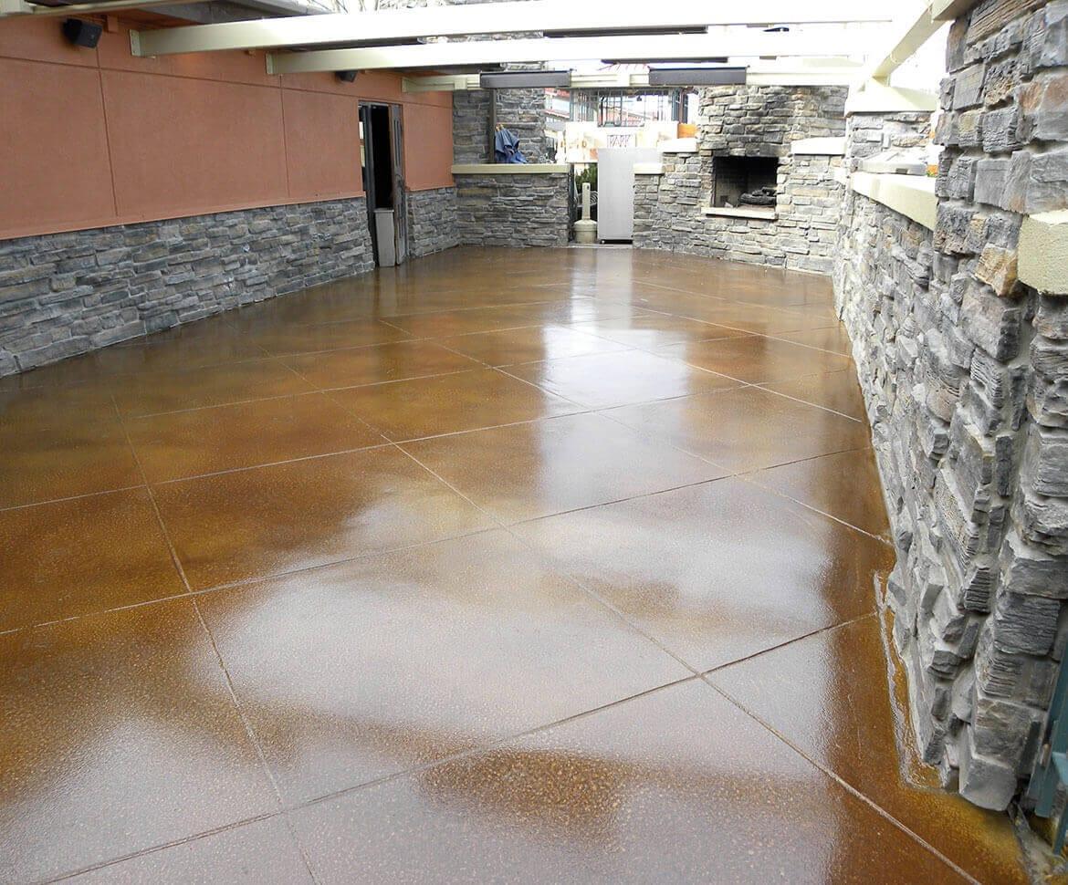 Glossy amber stained concrete floor beside stone walls