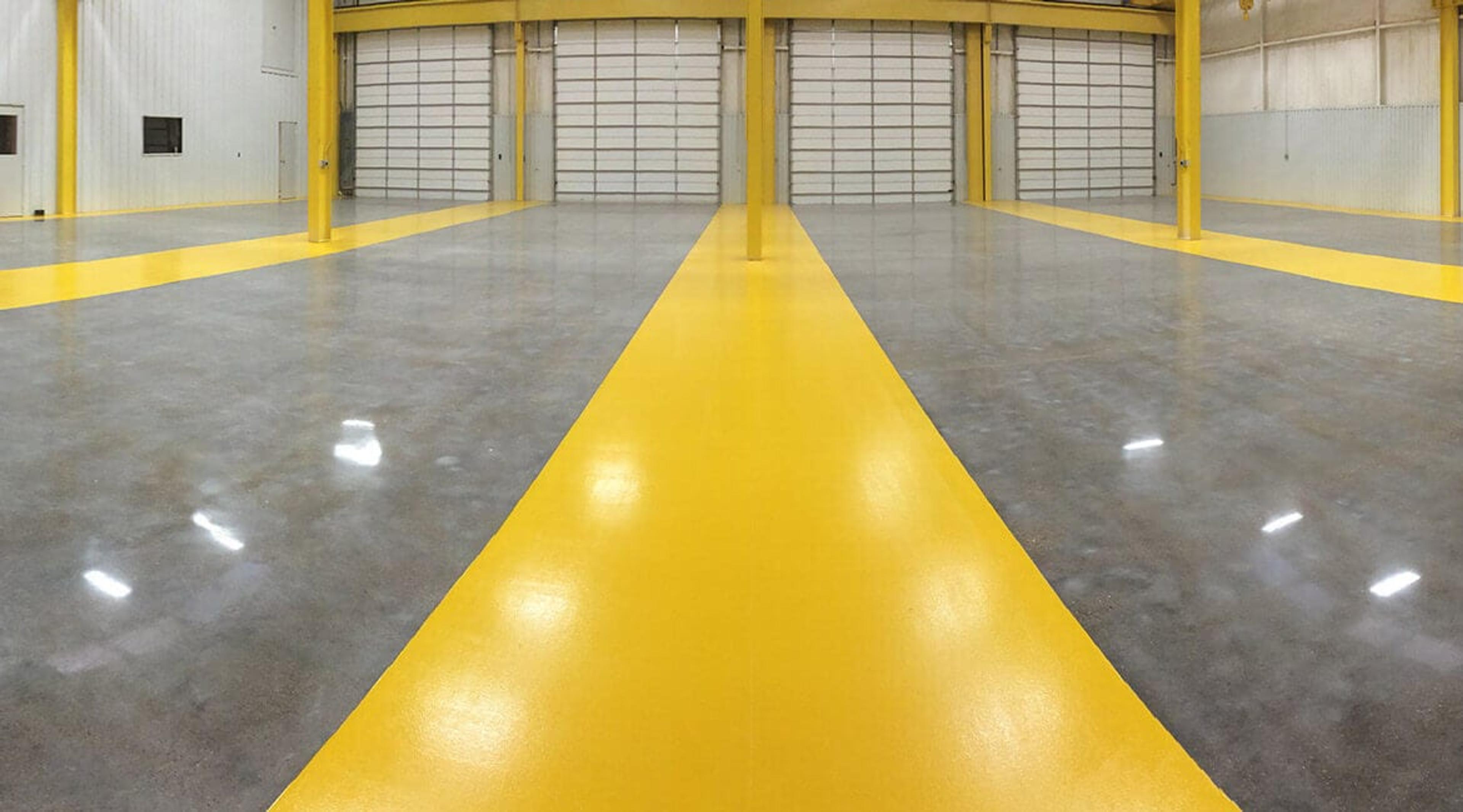 Polished concrete floor with a yellow safety lane in a loading bay