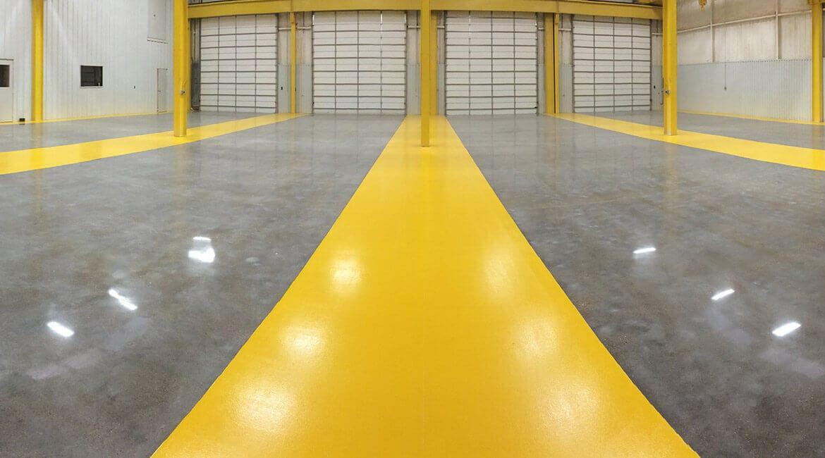 Polished concrete floor with a yellow safety lane in a loading bay