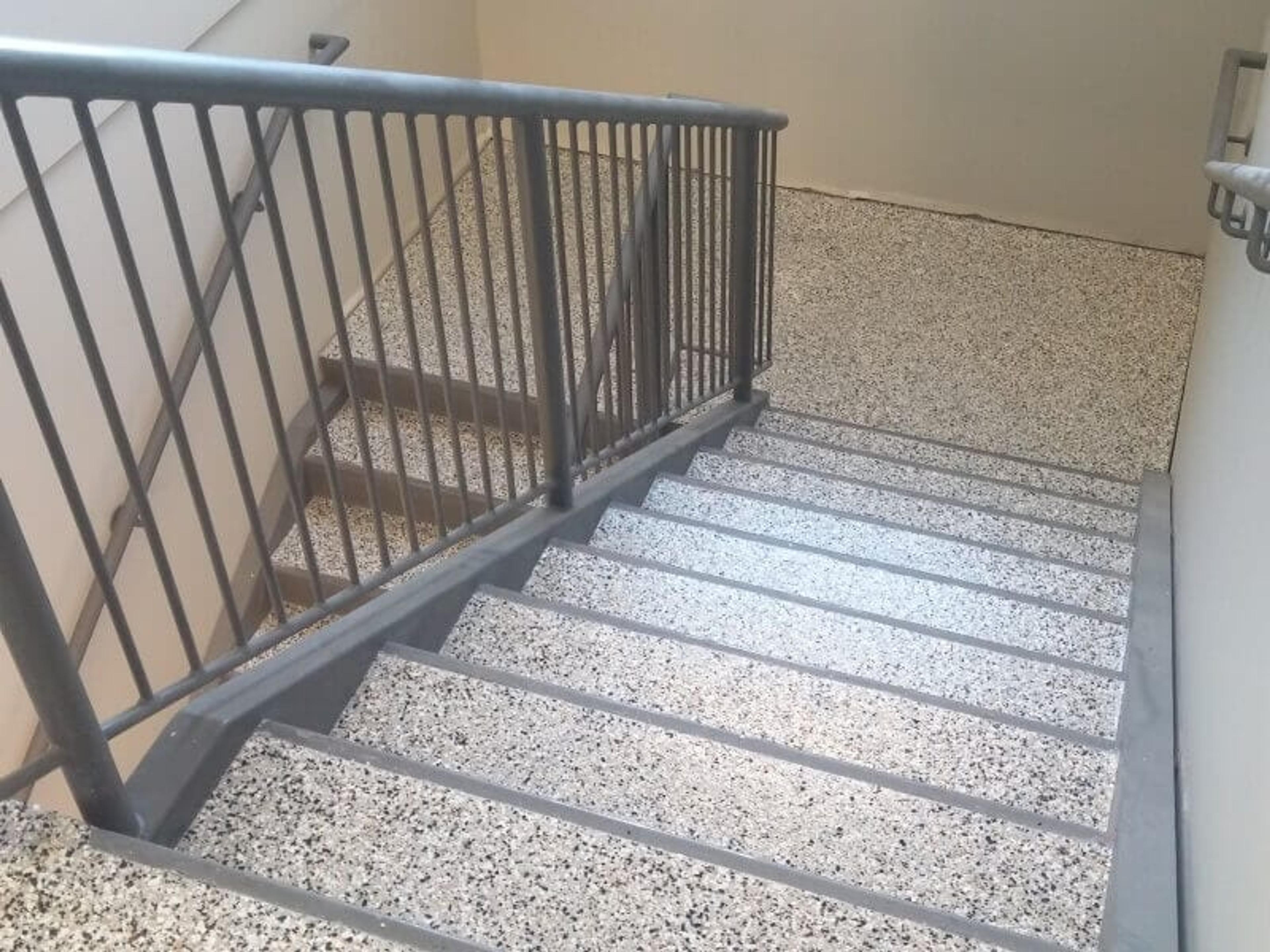 Flake epoxy coating on a concrete staircase with a metal railing