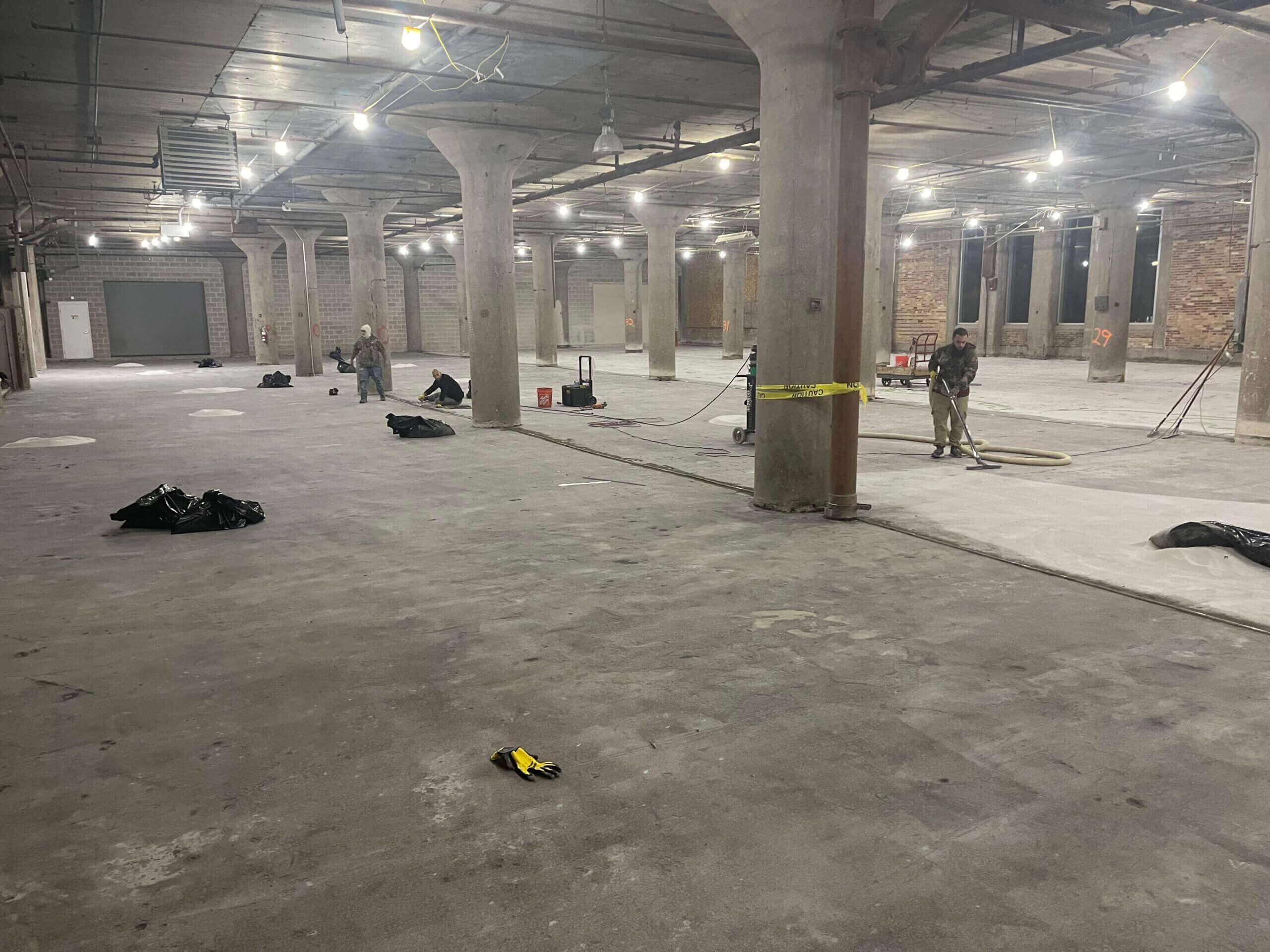 Concrete floor being restored in a large industrial building with columns