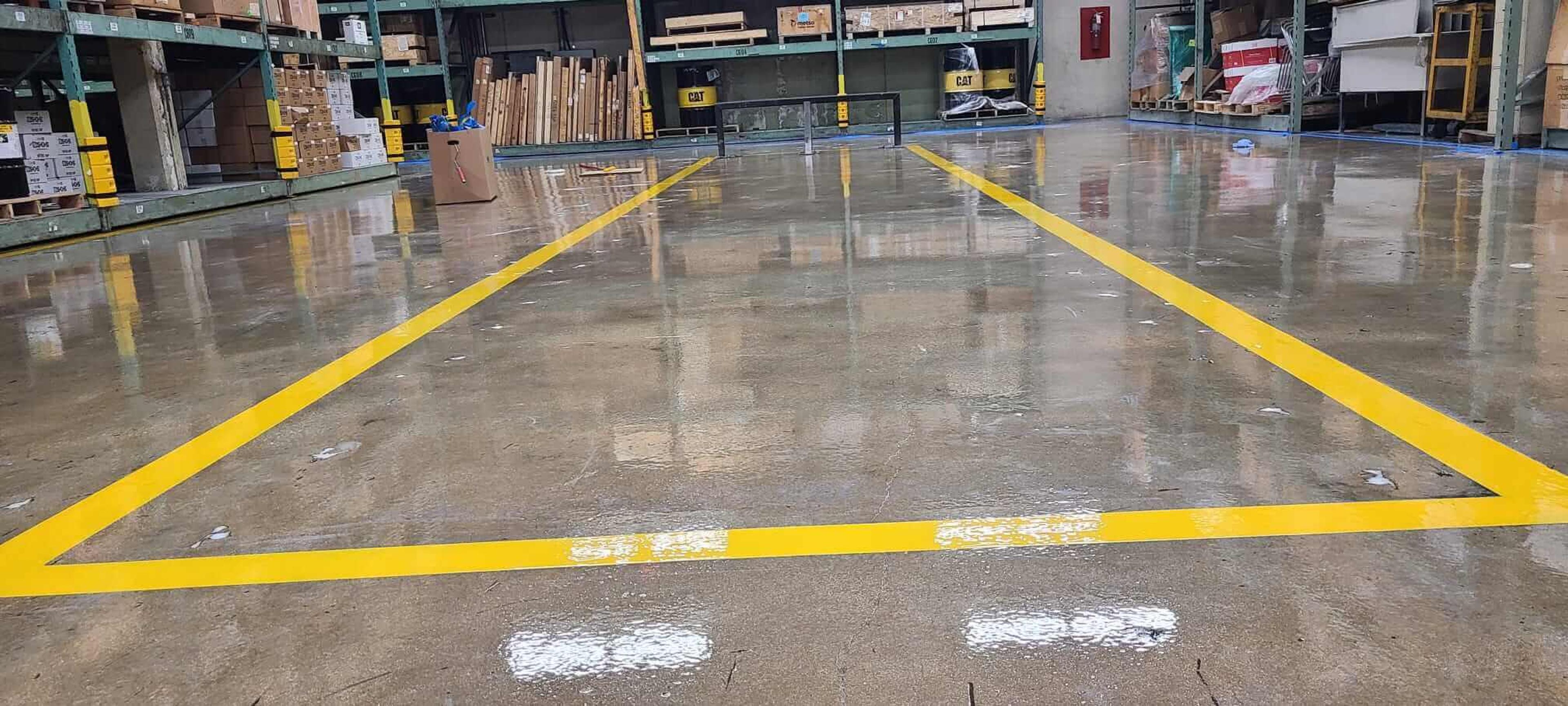 Polished concrete floor with yellow safety lines in a warehouse