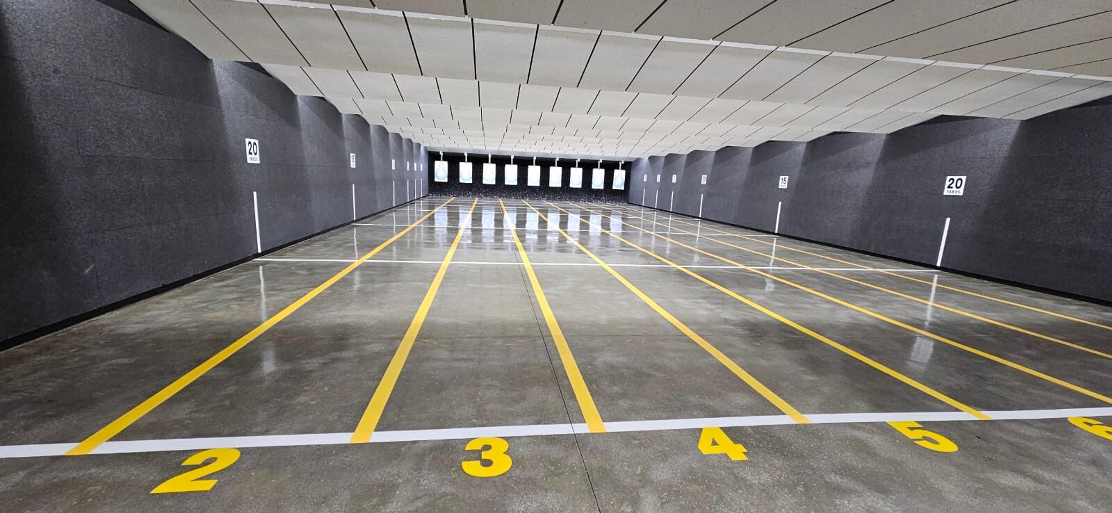 Sealed concrete floor with painted yellow lane lines in an indoor shooting range