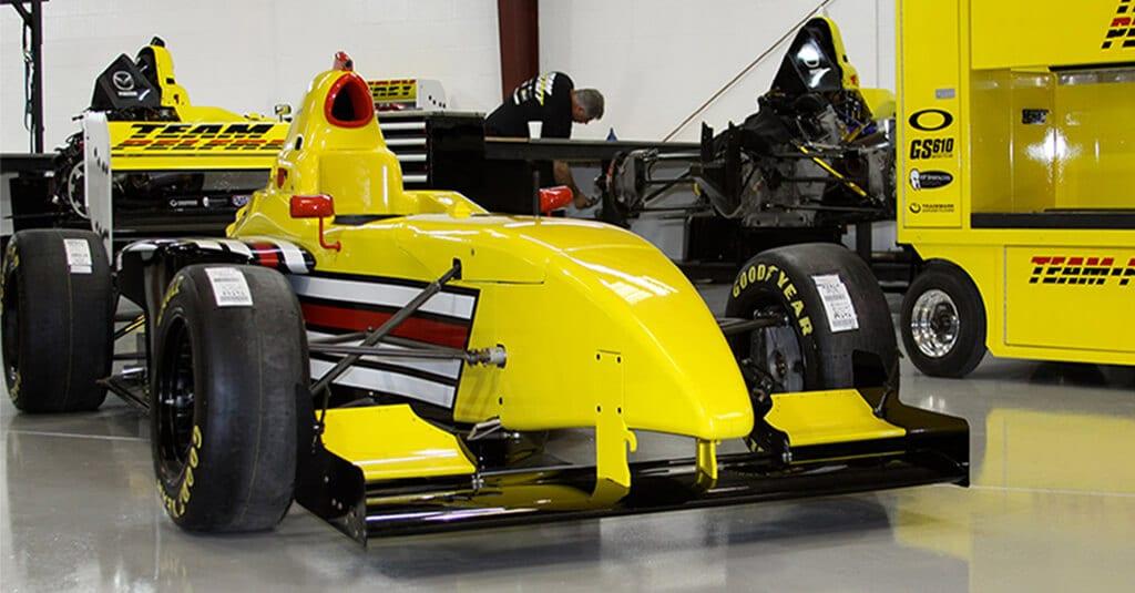 Yellow open-wheel race car on a light gray epoxy garage floor