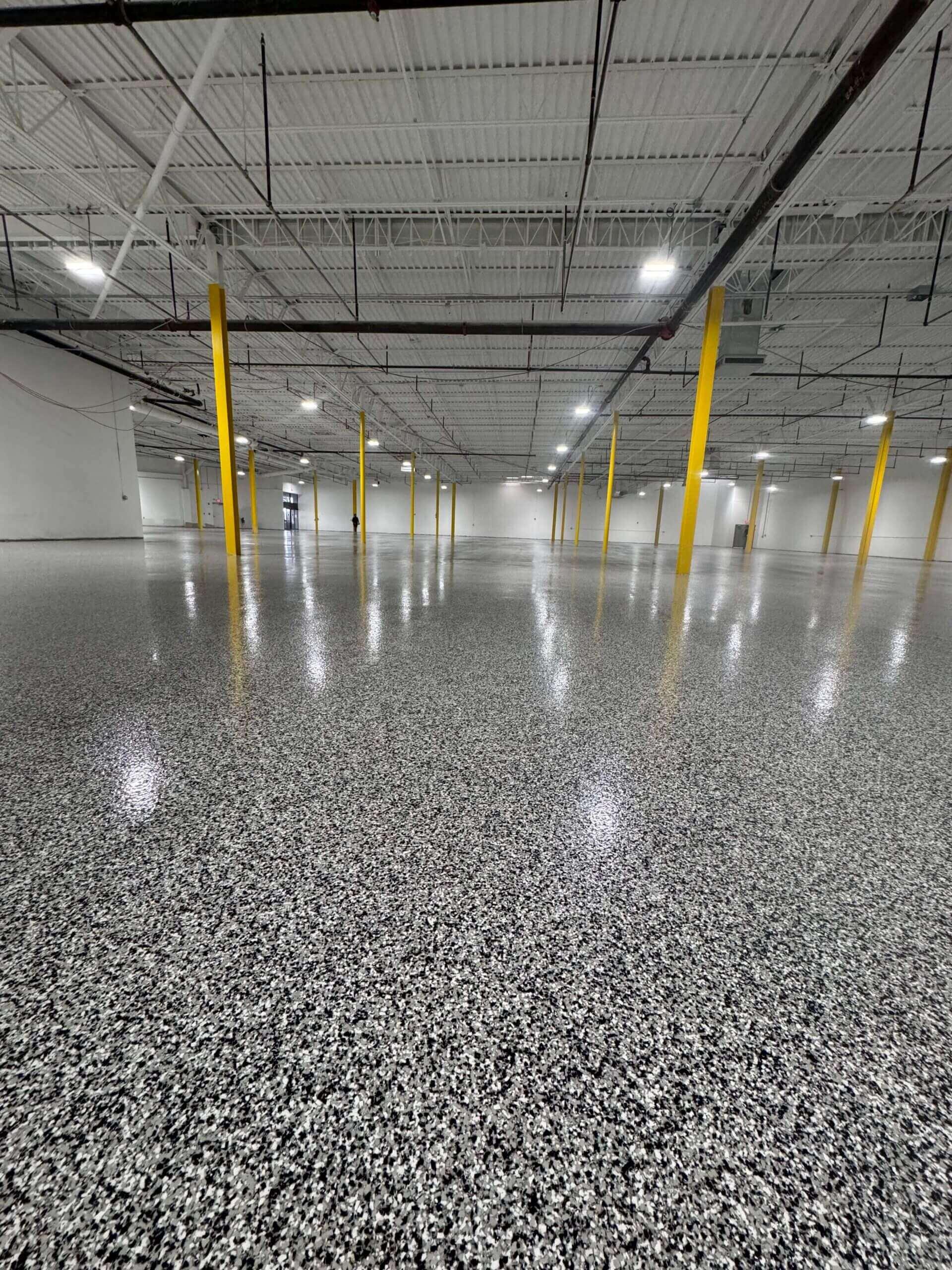 Speckled flake epoxy floor in a large warehouse with yellow columns