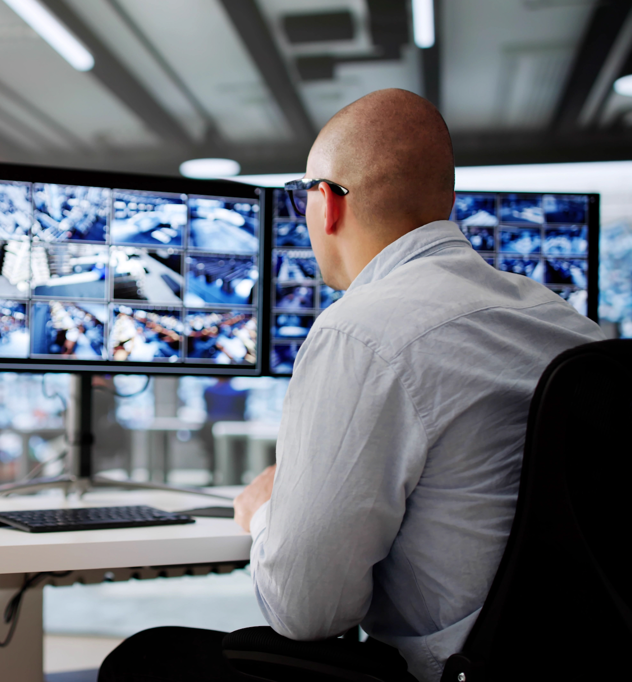 Professional video monitoring expert assessing cameras on two monitors. 