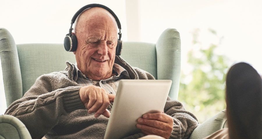Elderly man with headphones on and using an ipad