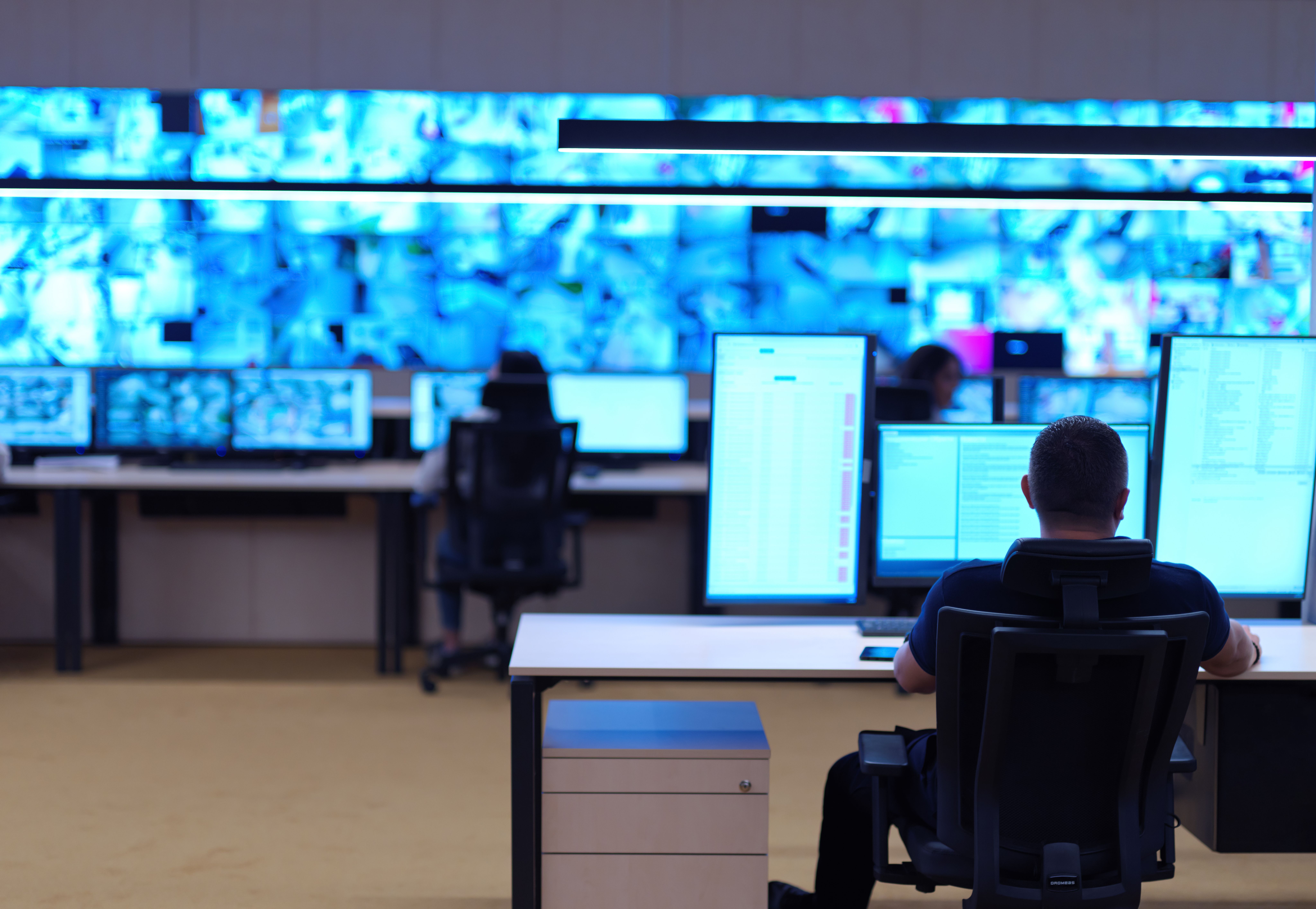 Male business security monitoring expert watching screens.