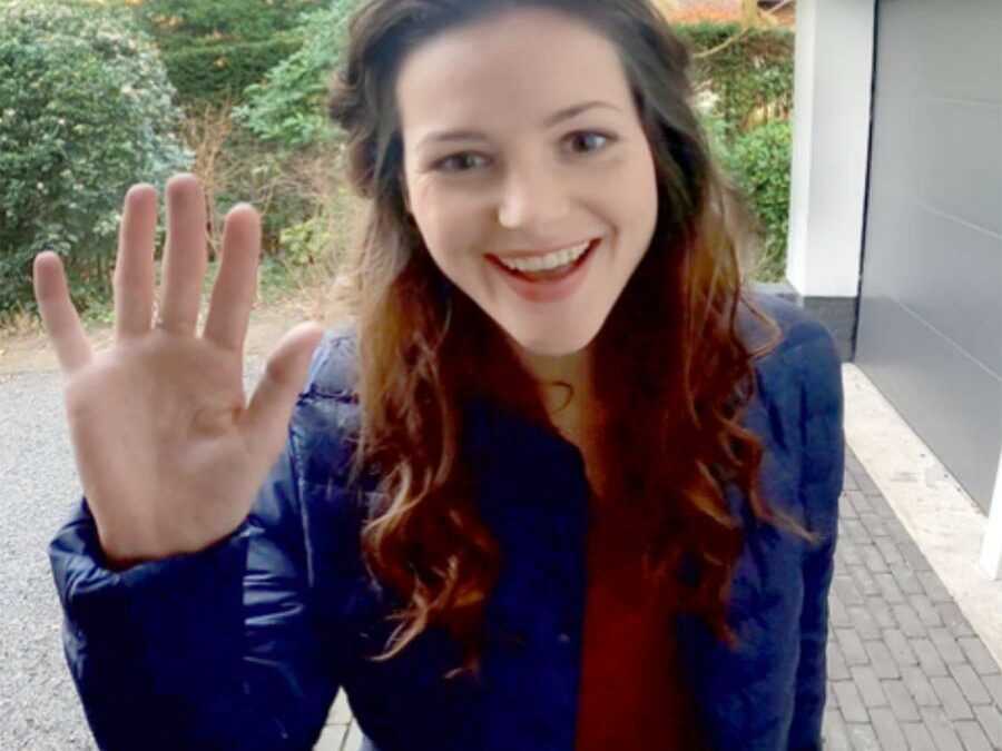 Smiling lady waving at a doorbell camera