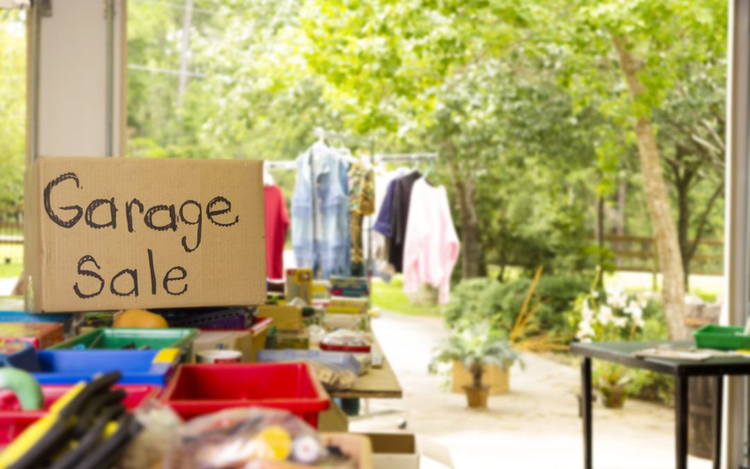 Items laid out outside with a cardboard sign saying "Garage sale"