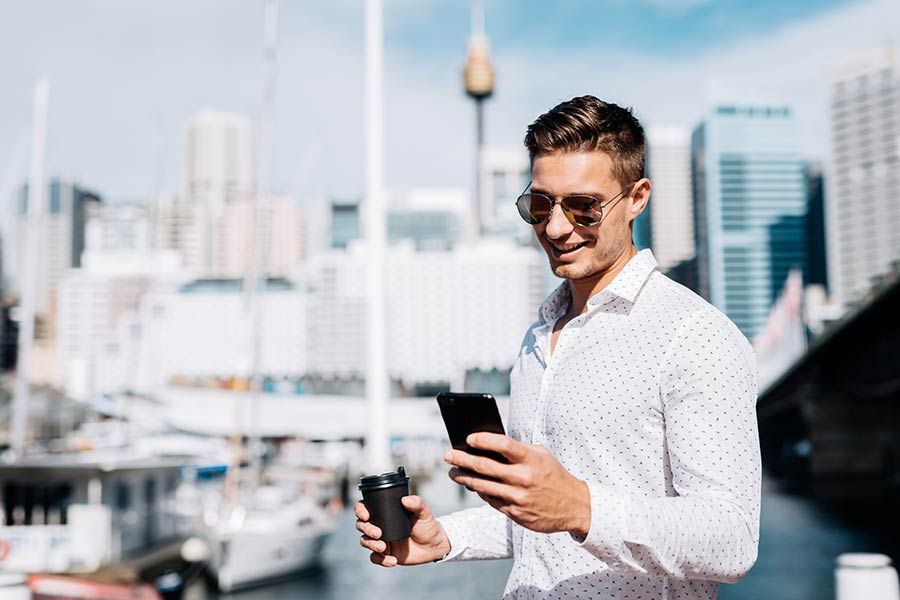 Man in sunglasses holding coffee and phone
