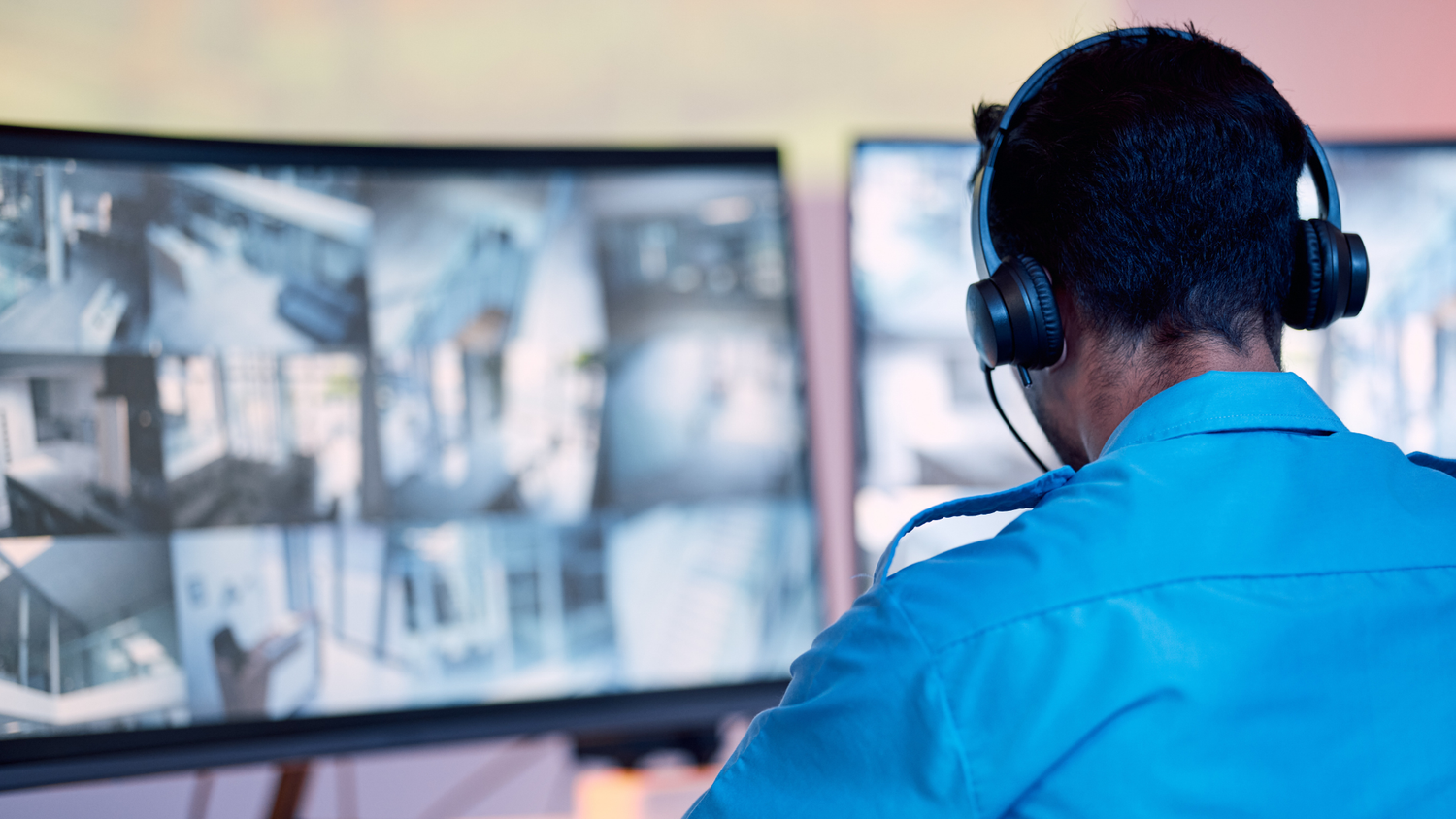 Male business security monitoring expert watching screens.