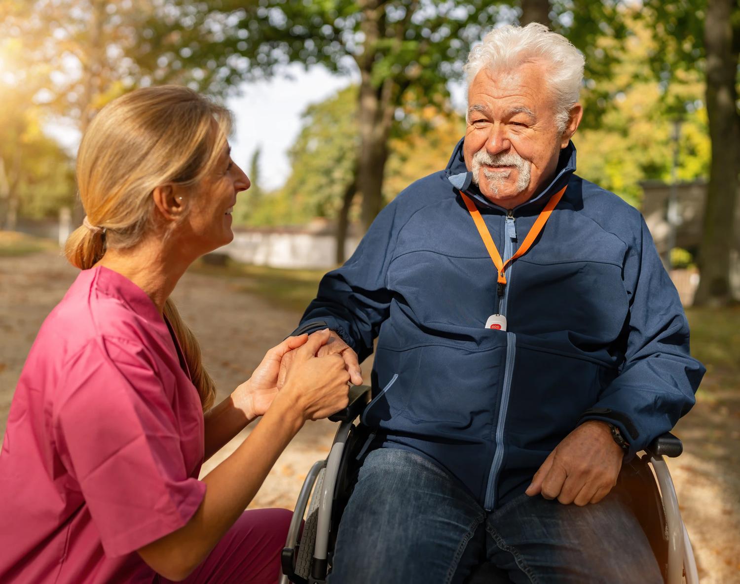 Carer holding hand of man in wheelchair
