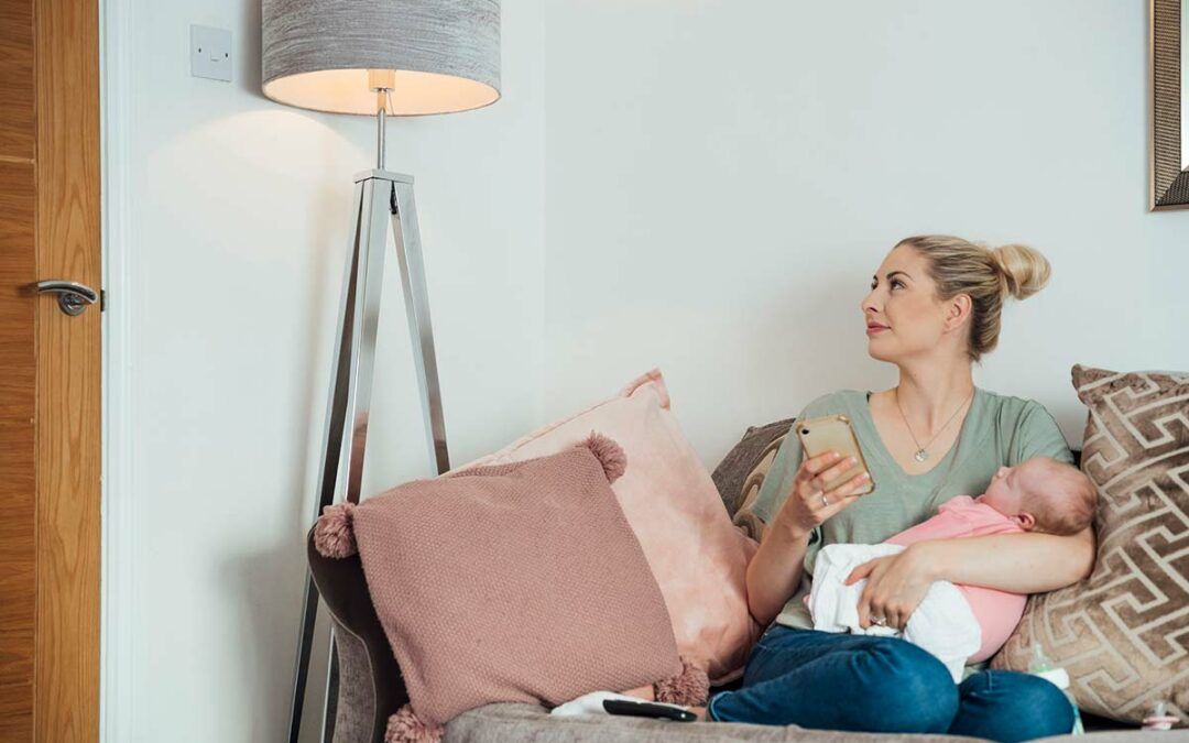 lady sitting on a couch with her baby and holding a phone