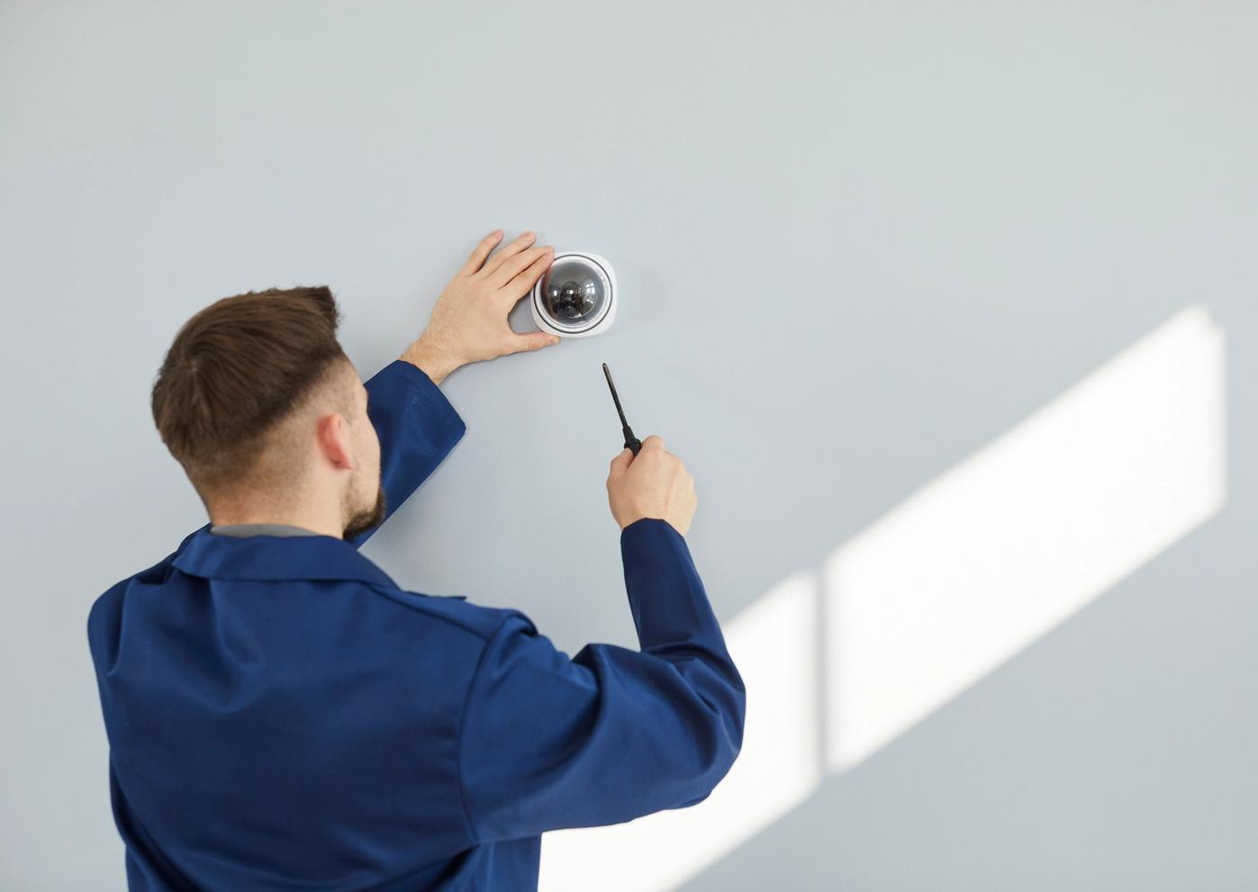 Man in blue jumpsuit installs CCTV
