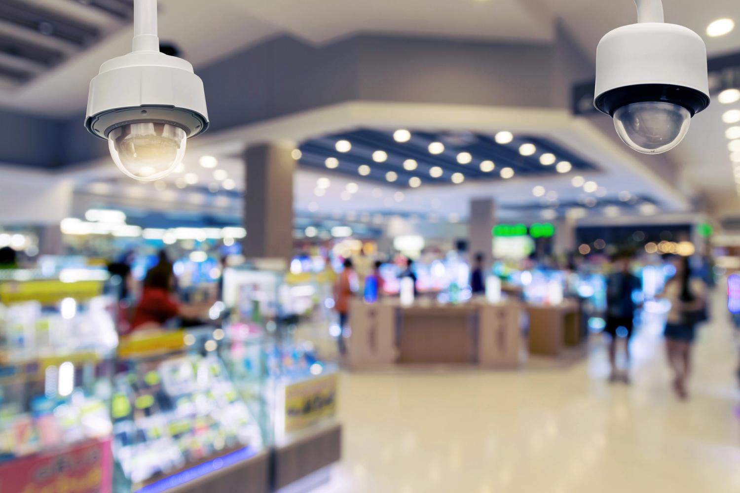 2 ceiling cameras and a blurred shopping centre in the background