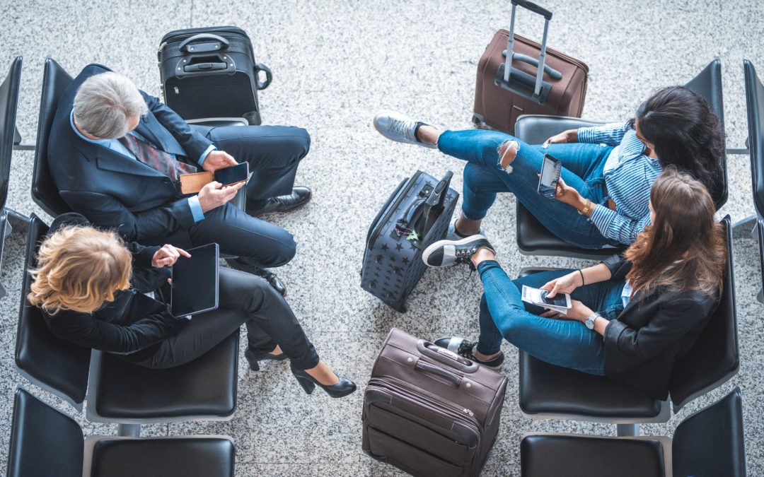 Bird's eye view of four people sitting with luggage at an airport.