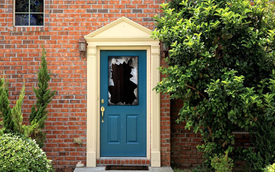 A blue door with broken glass, suggesting a break-in