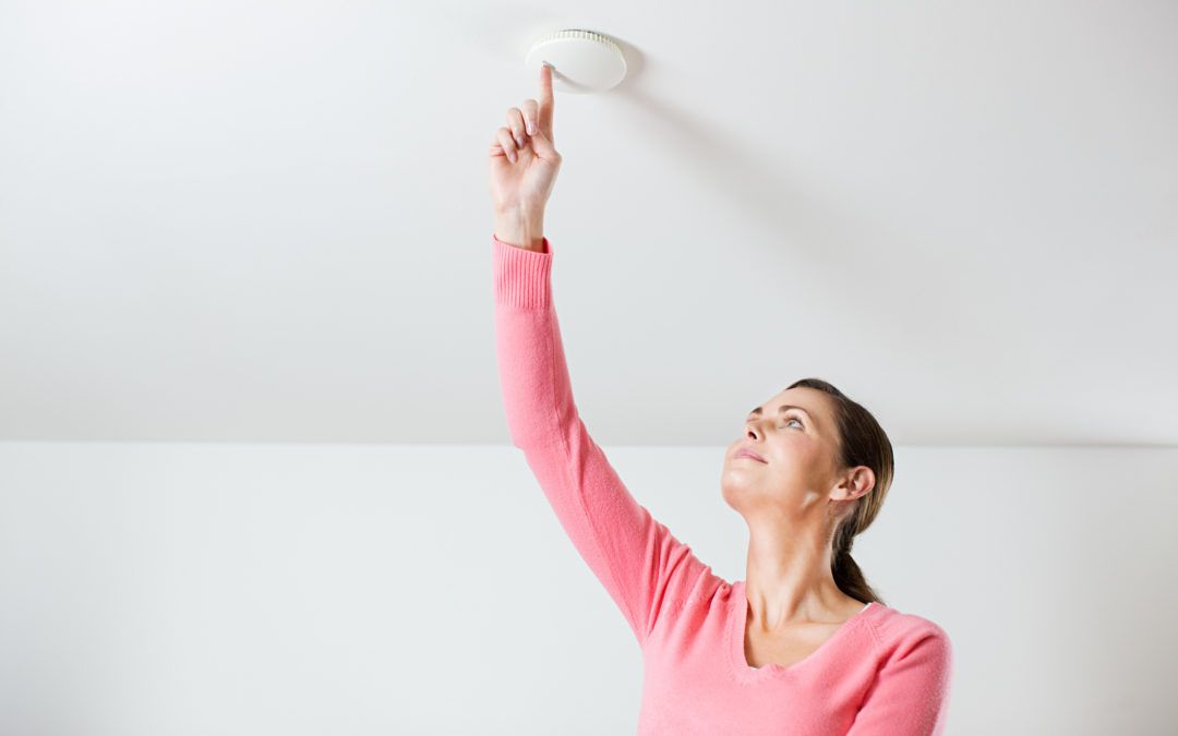 Lady pressing a button on the smoke alarm