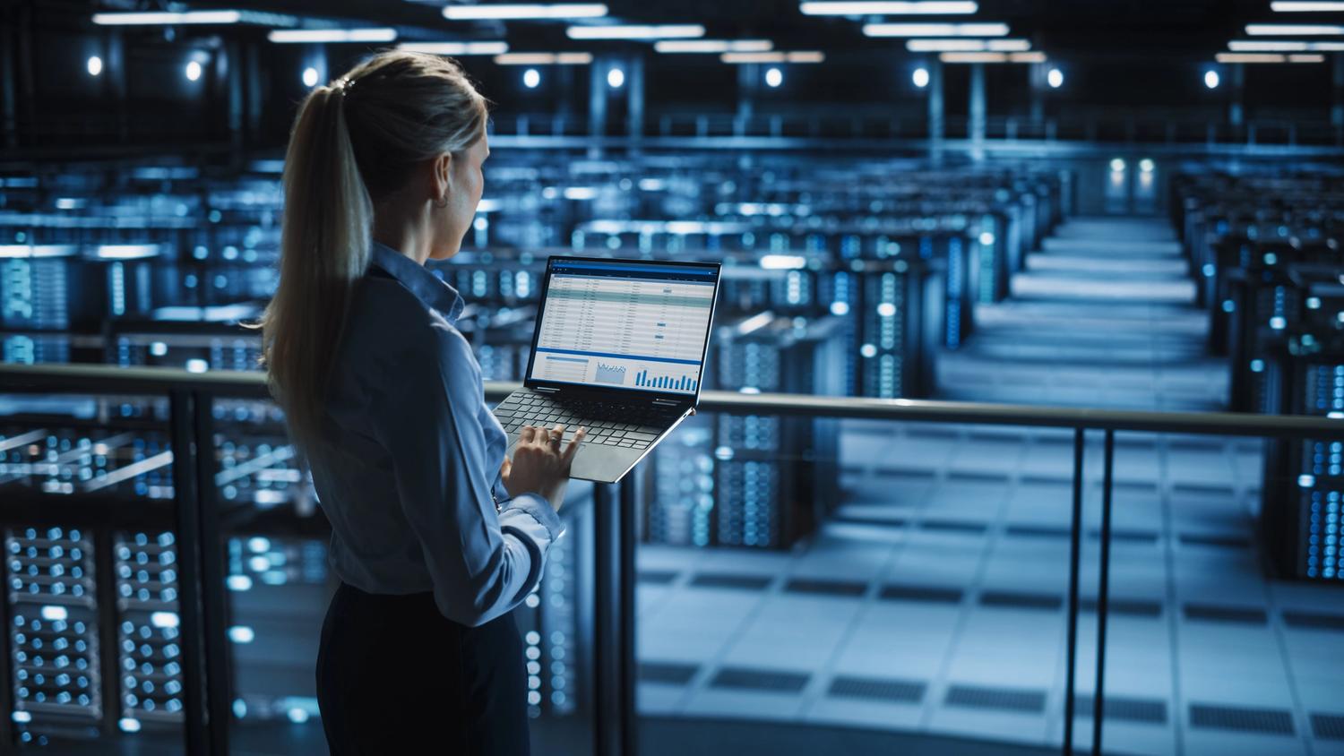 woman with laptop overseeing data warehouse