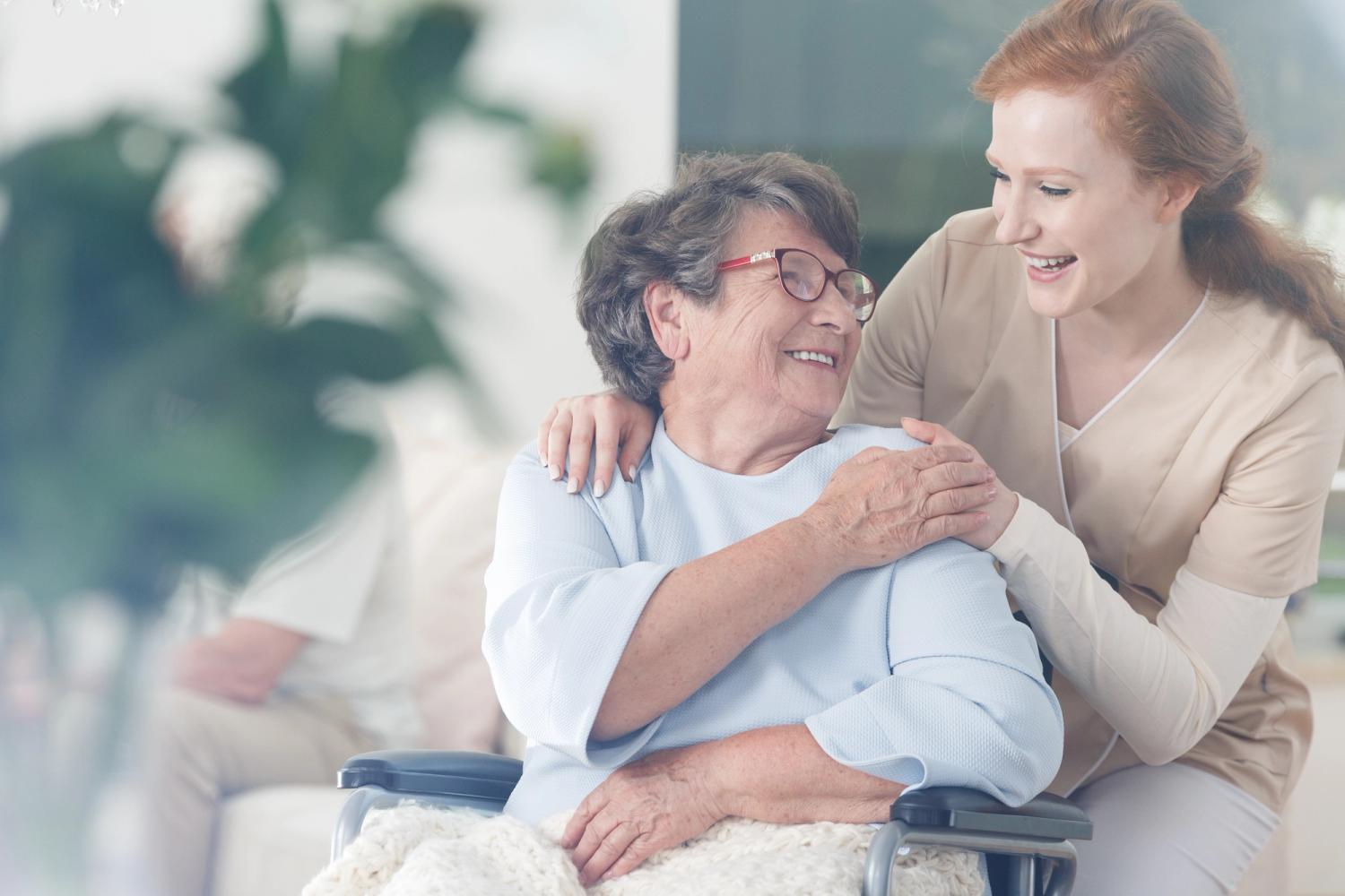 carer with woman in wheelchair holding hands