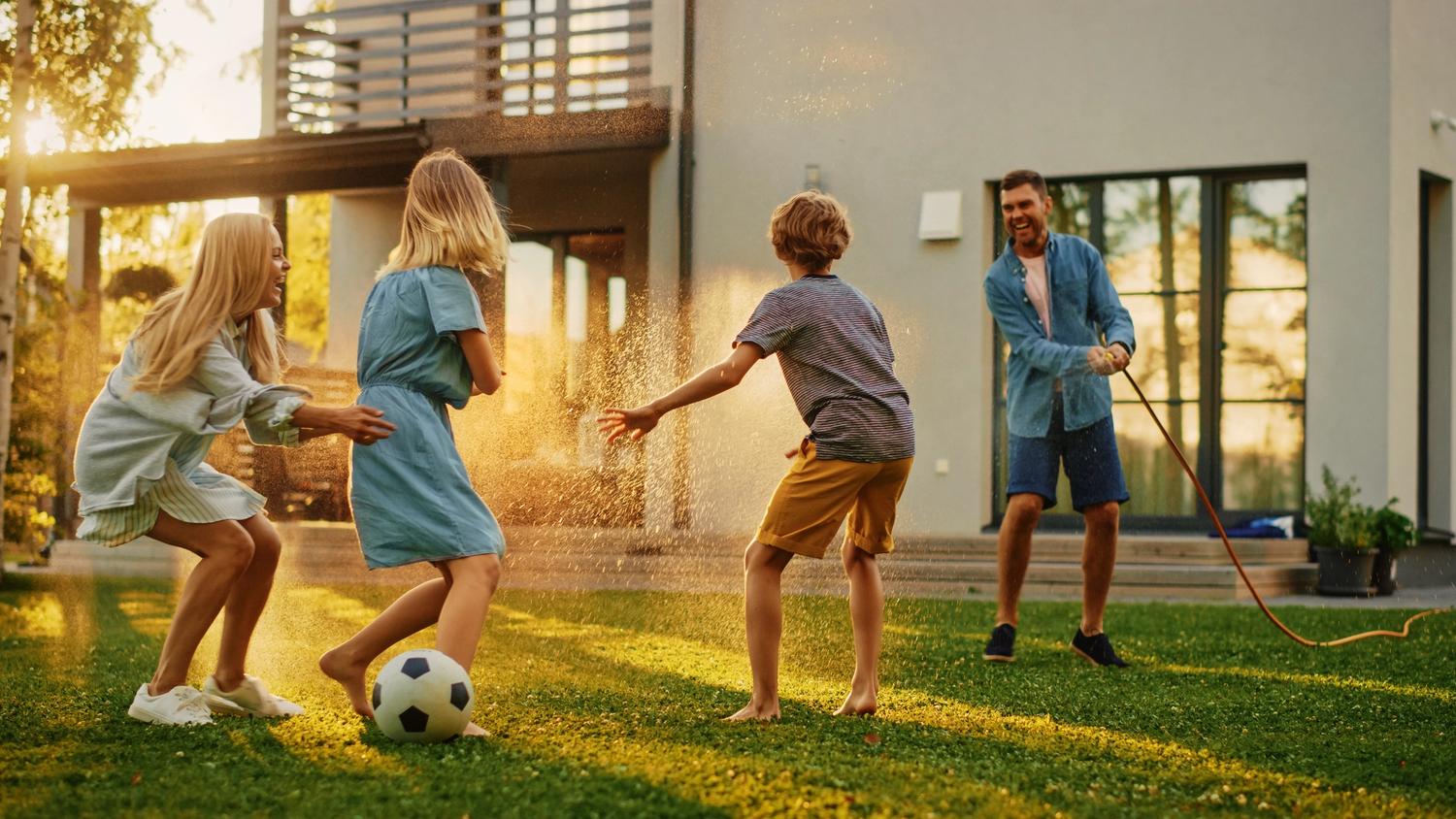 dad with three children playing with garden hose