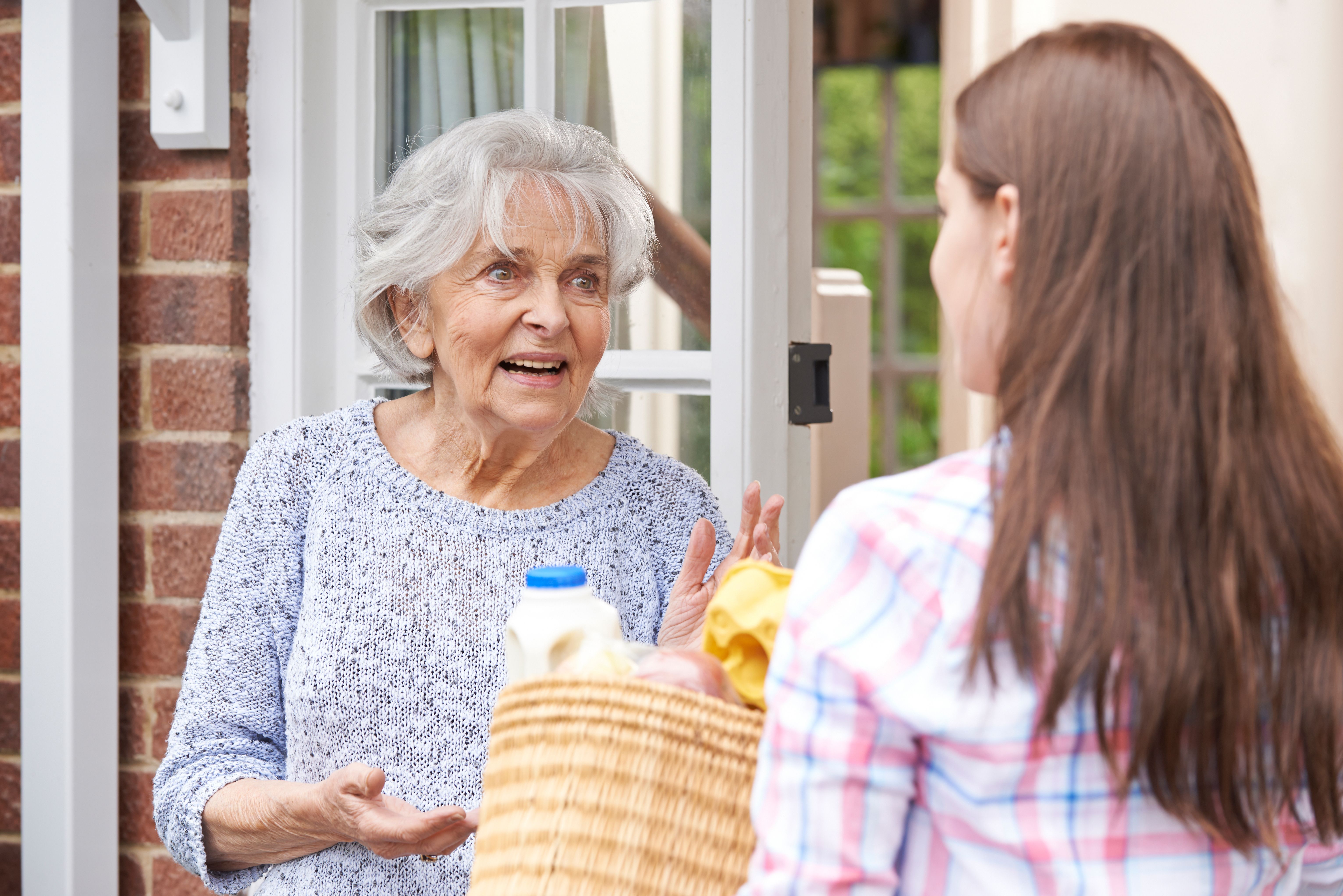 A lady giving a basket of groceries to another lady