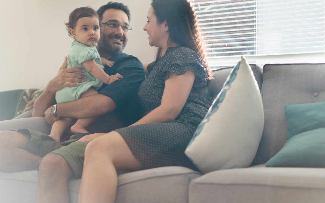 A couple holding their baby and sitting down