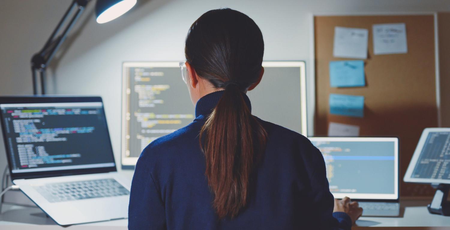 female engineer coding on multiple screens