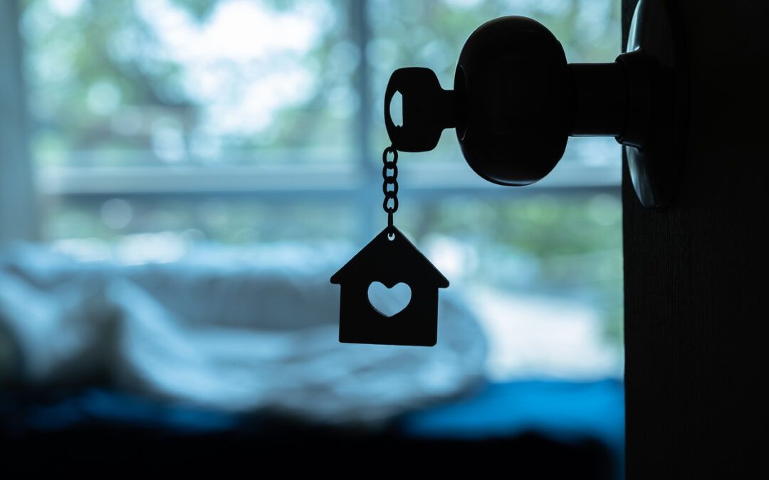Silhouette of a house key with a house shaped keychain, stuck in a doorknob