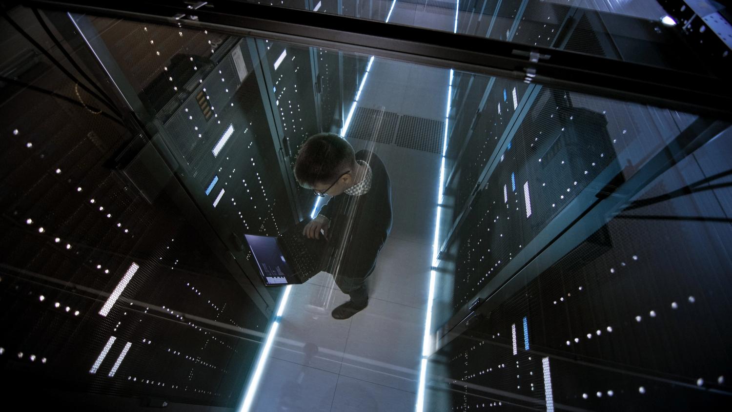 Aerial view of IT worker with laptop in a data centre.