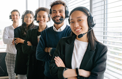 A group of smiling employees with headsets on and folded arms