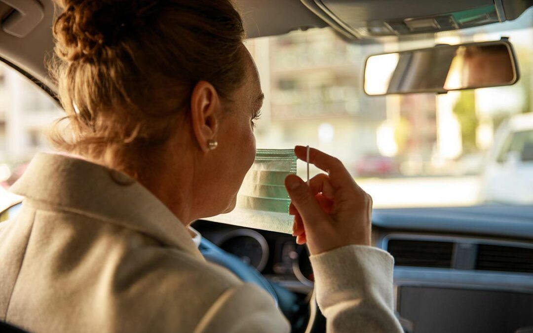 A woman holding a facemask while driving.