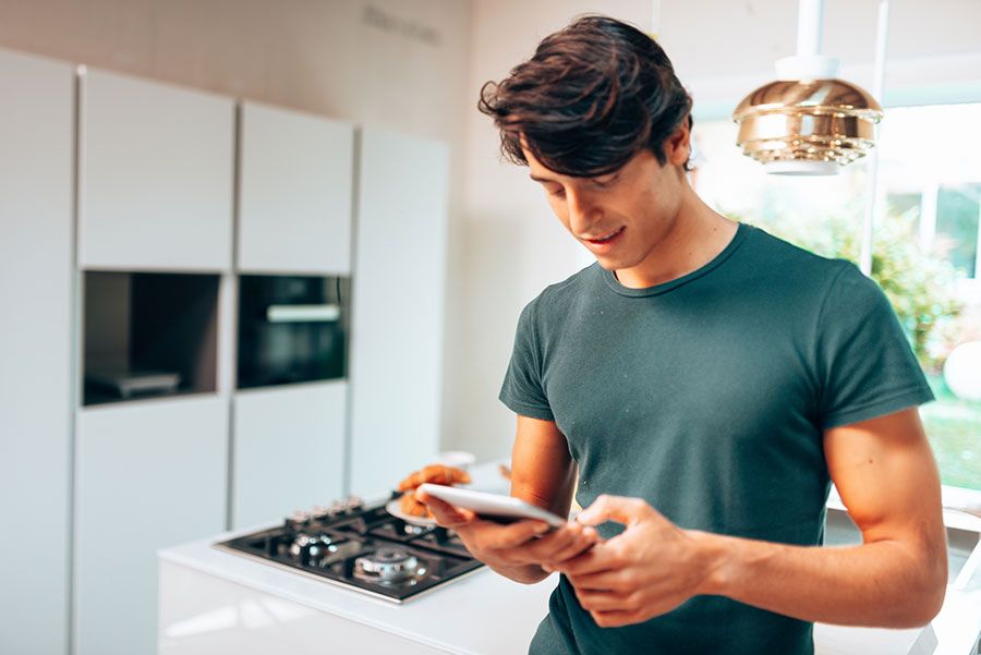 Man in the kitchen looking at his phone