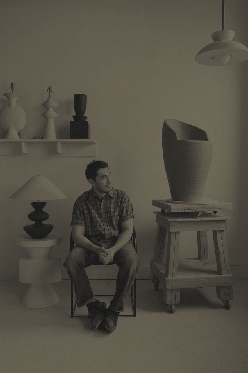 Danny Kaplan seated among ceramic lamps and sculpture